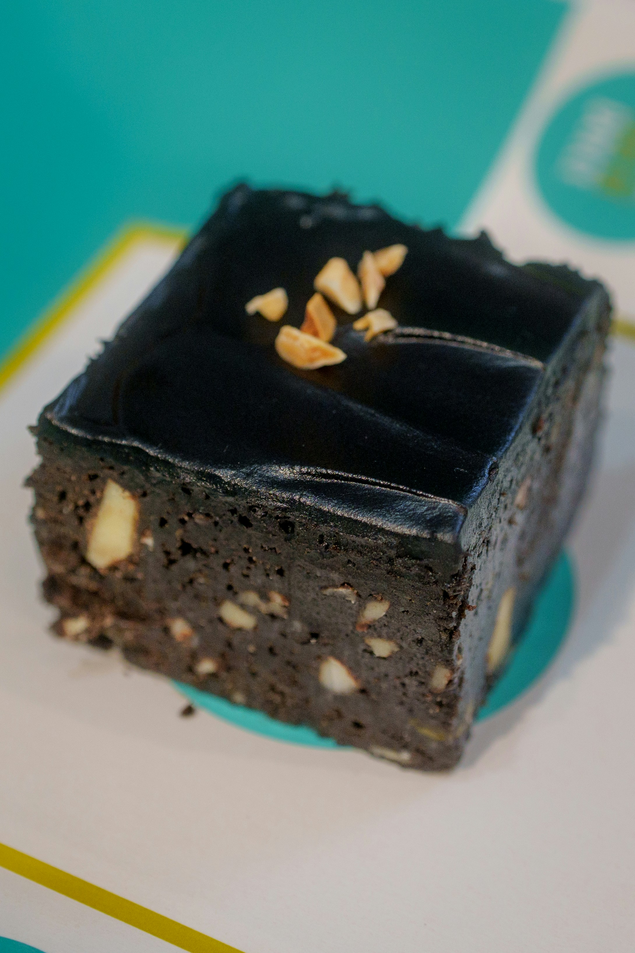 A dark chocolate brownie topped with glossy glaze and chopped nuts