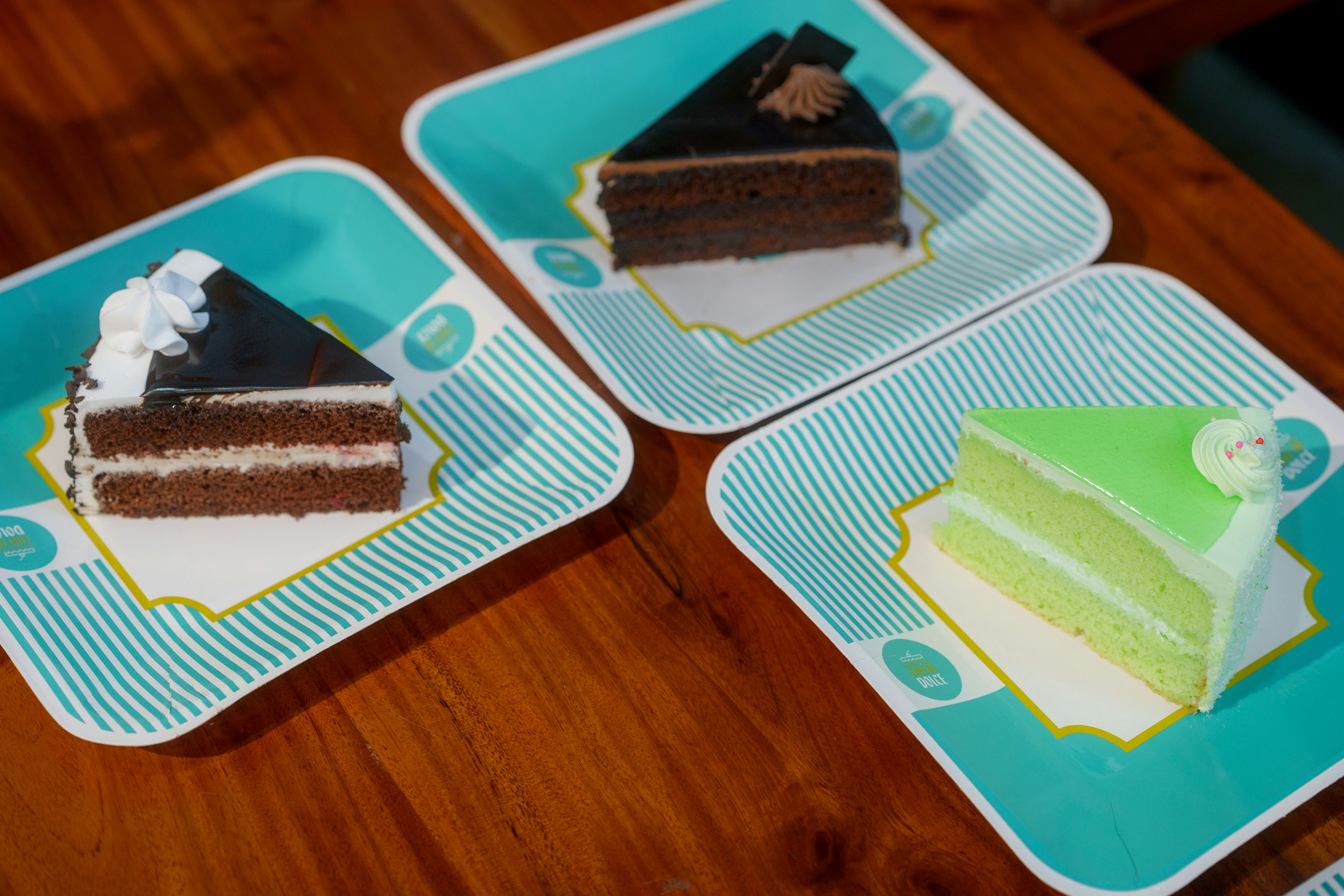 Three cake slices on turquoise patterned plates on a wooden table