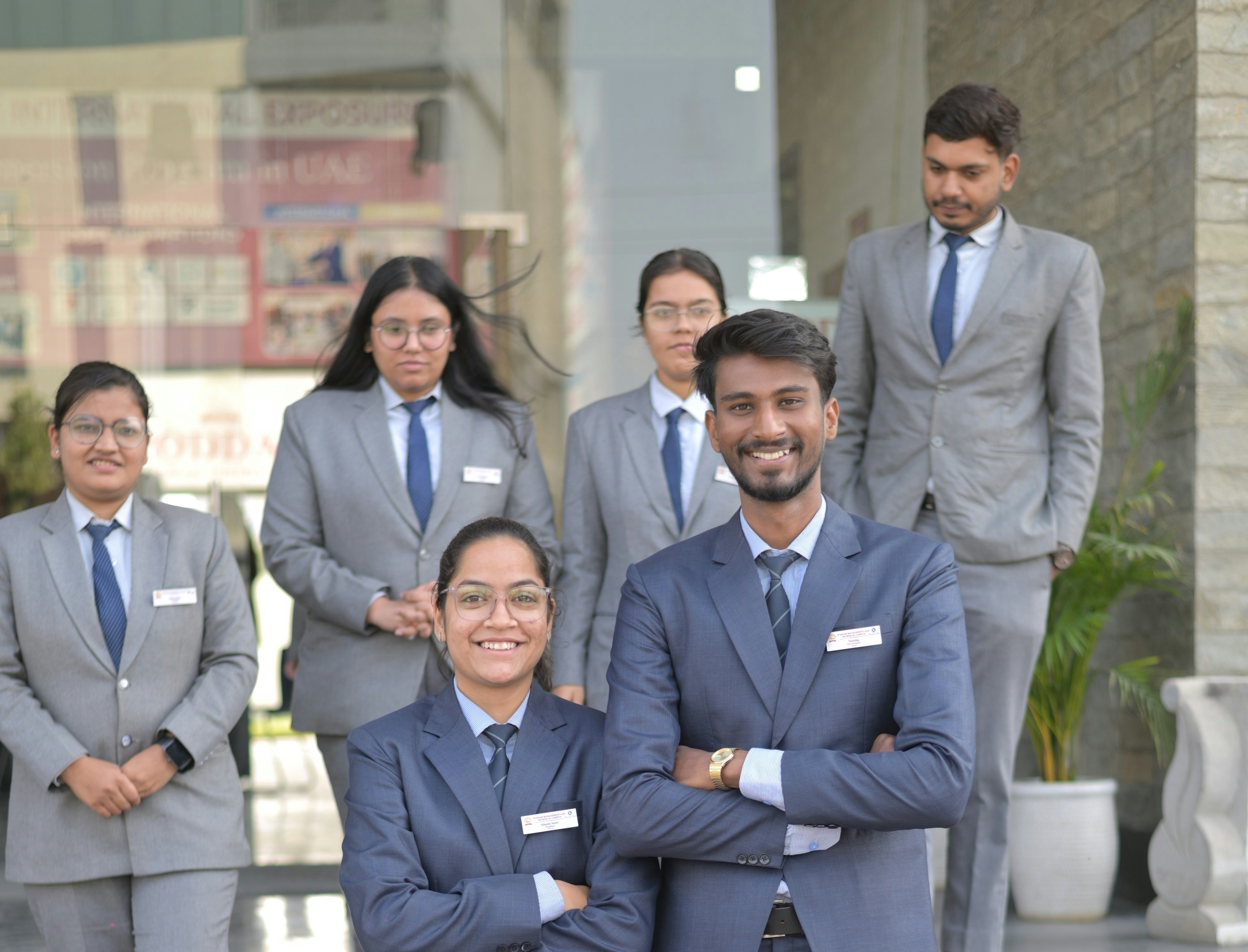 A group of people in matching business suits and ties outside a glass building