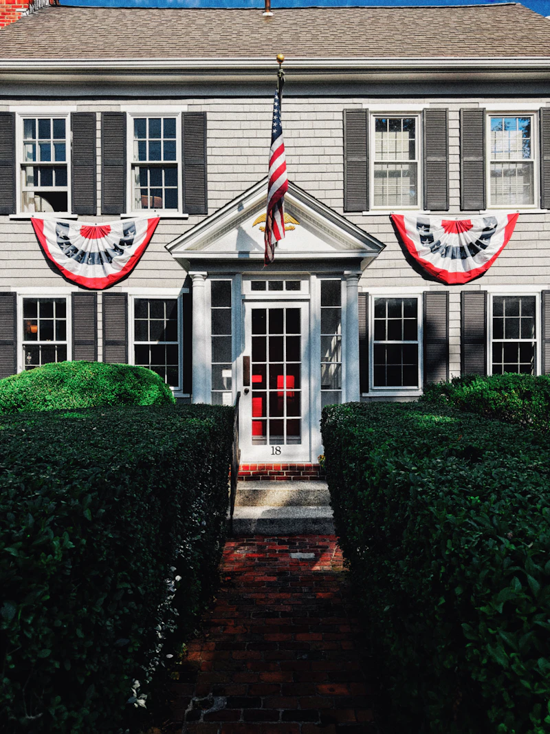 Colonial home with a brick path between two neatly trimmed hedges