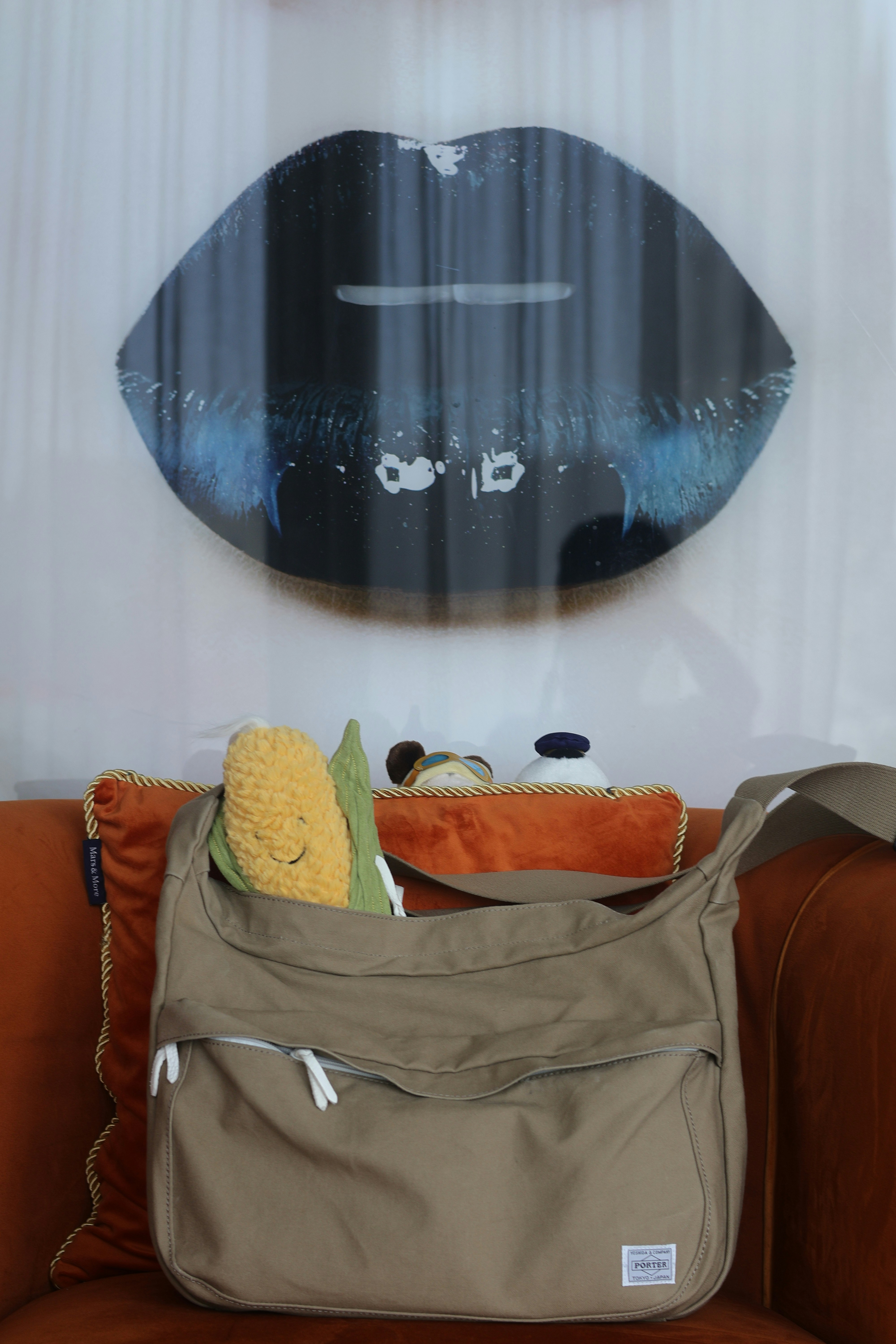 A corn plush toy in a beige shoulder bag on an orange armchair