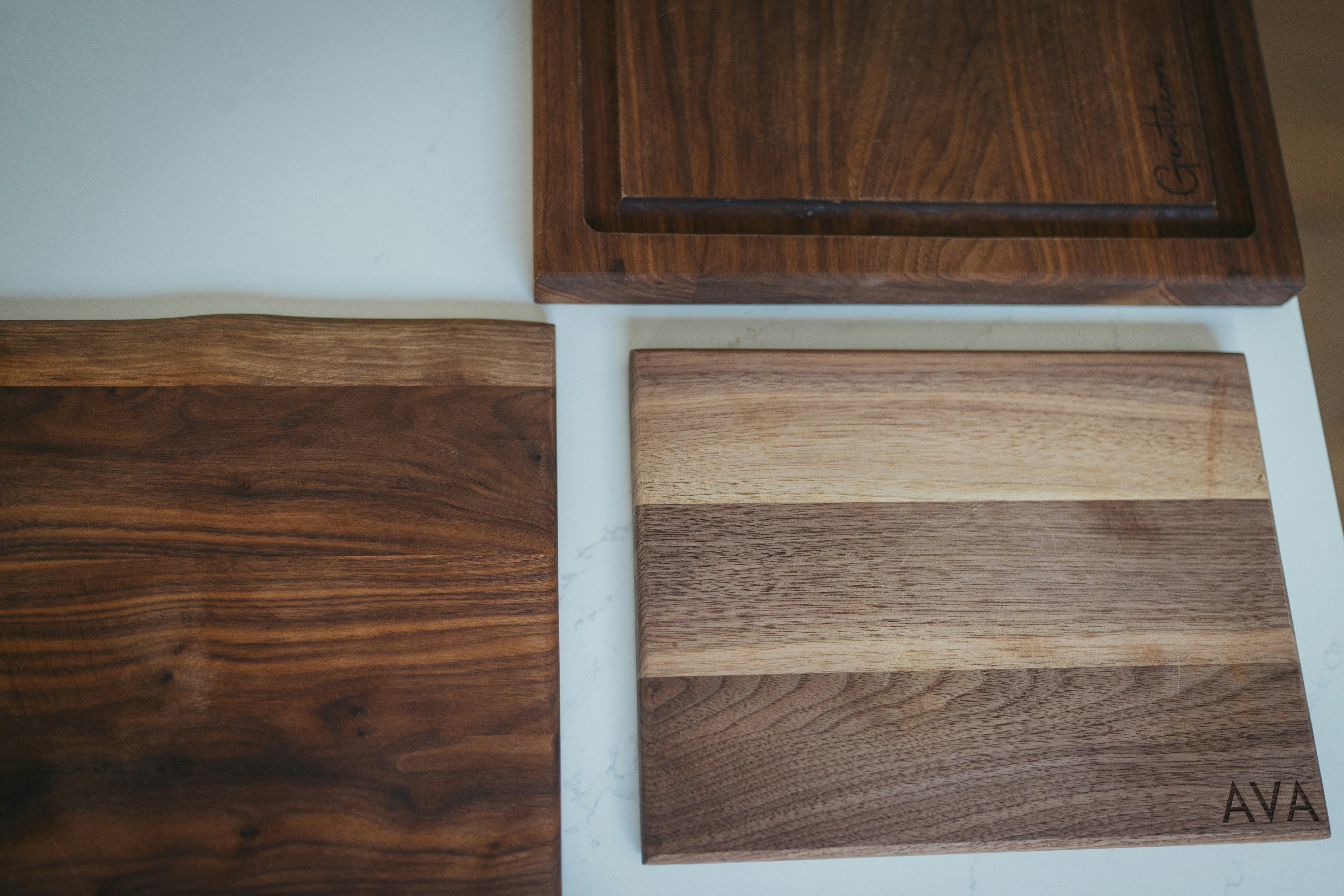 Three wooden serving boards with different grain lying on white marble.