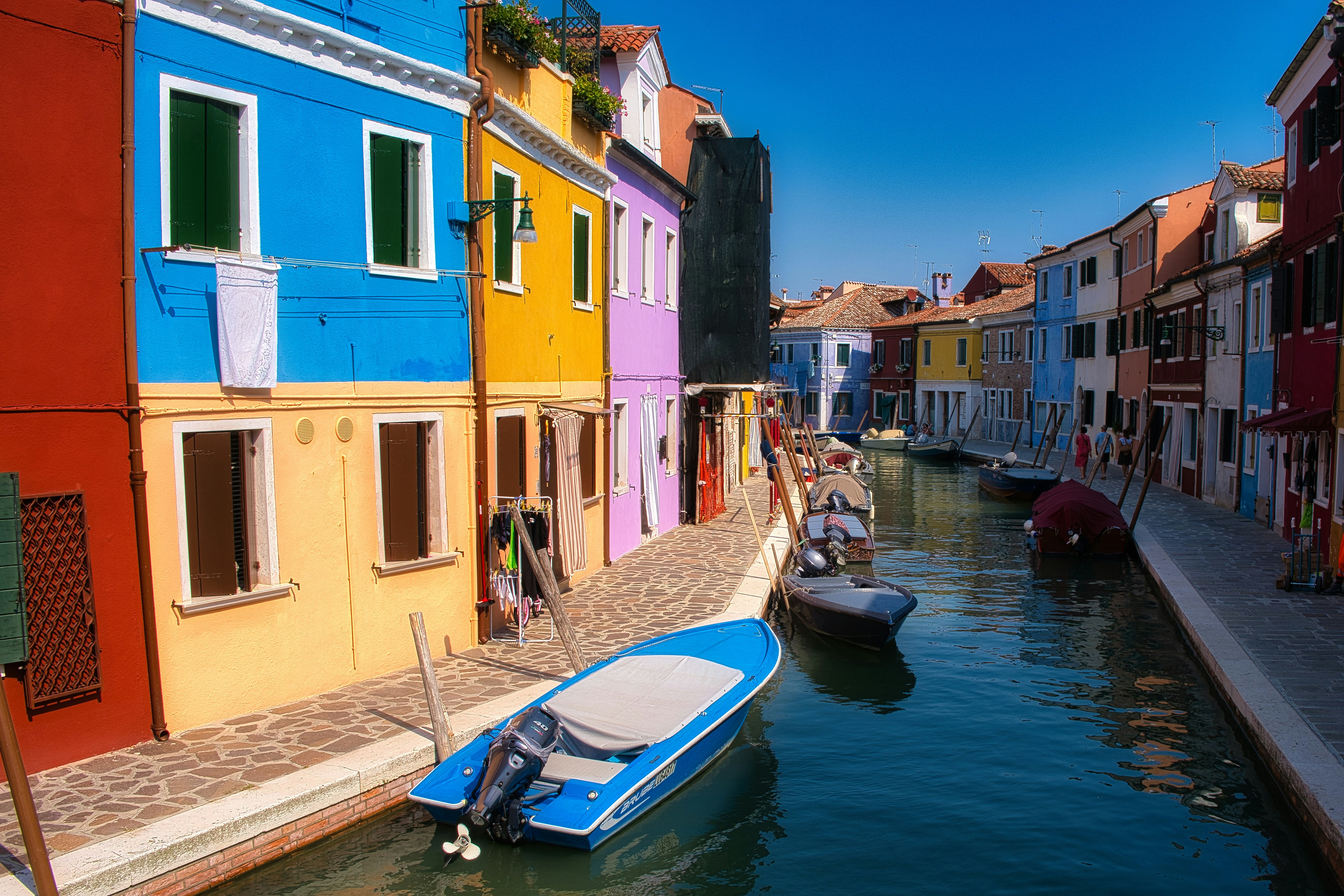 Colorful houses and moored boats along a canal in Burano