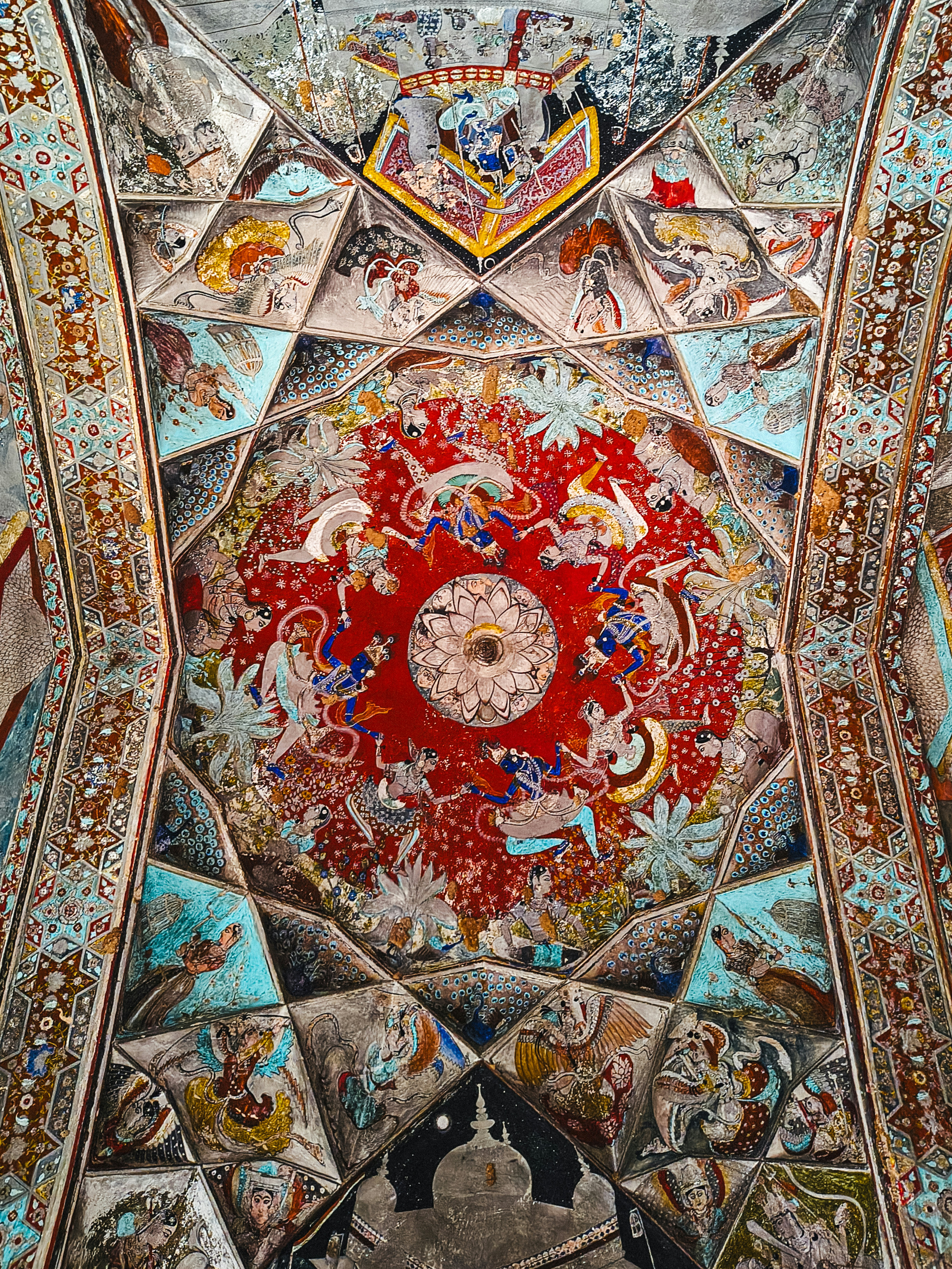 Fresque de plafond complexe avec un lotus central et des figures sur fond rouge