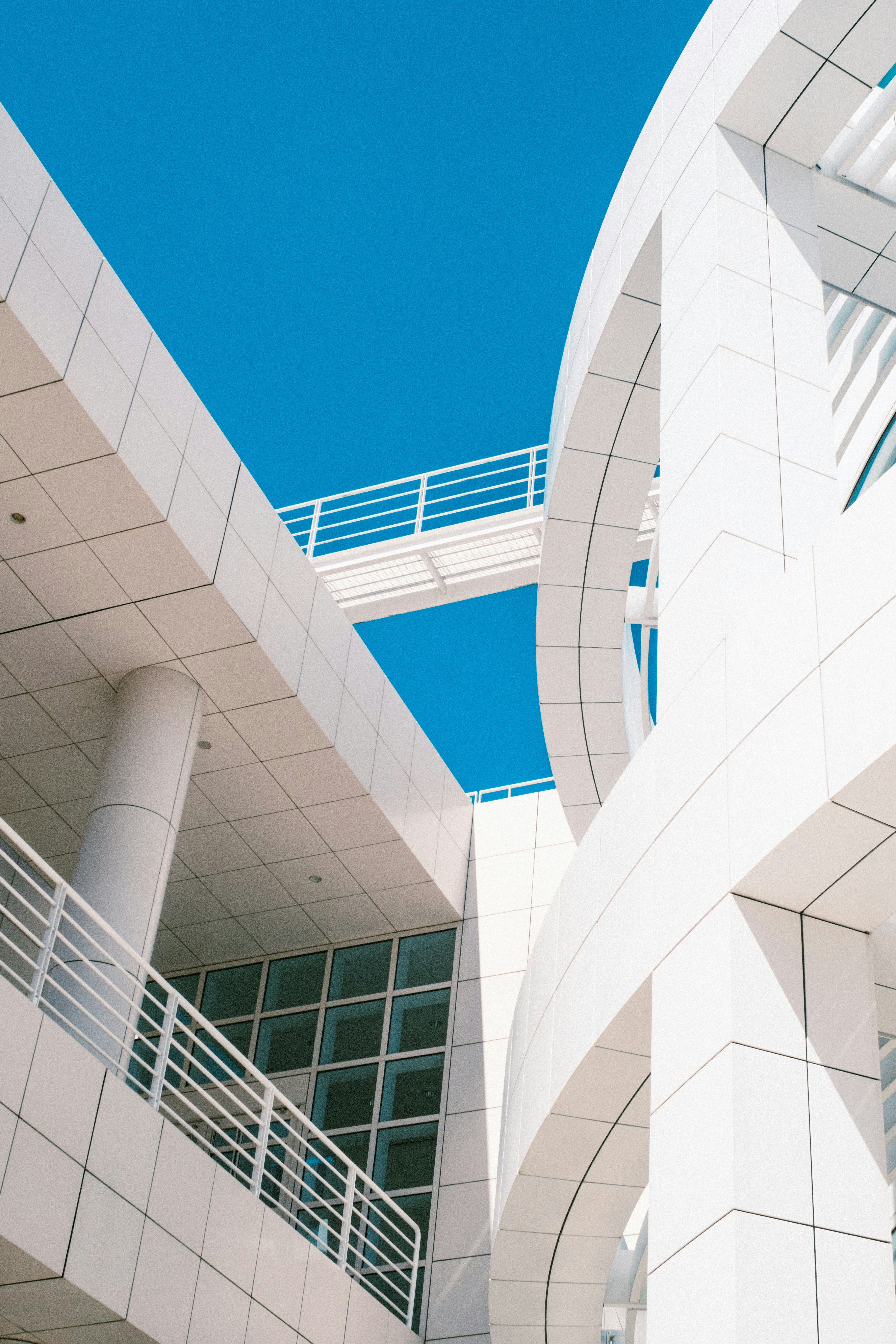 Modern white architecture with curved walls and a bridge against a clear blue sky