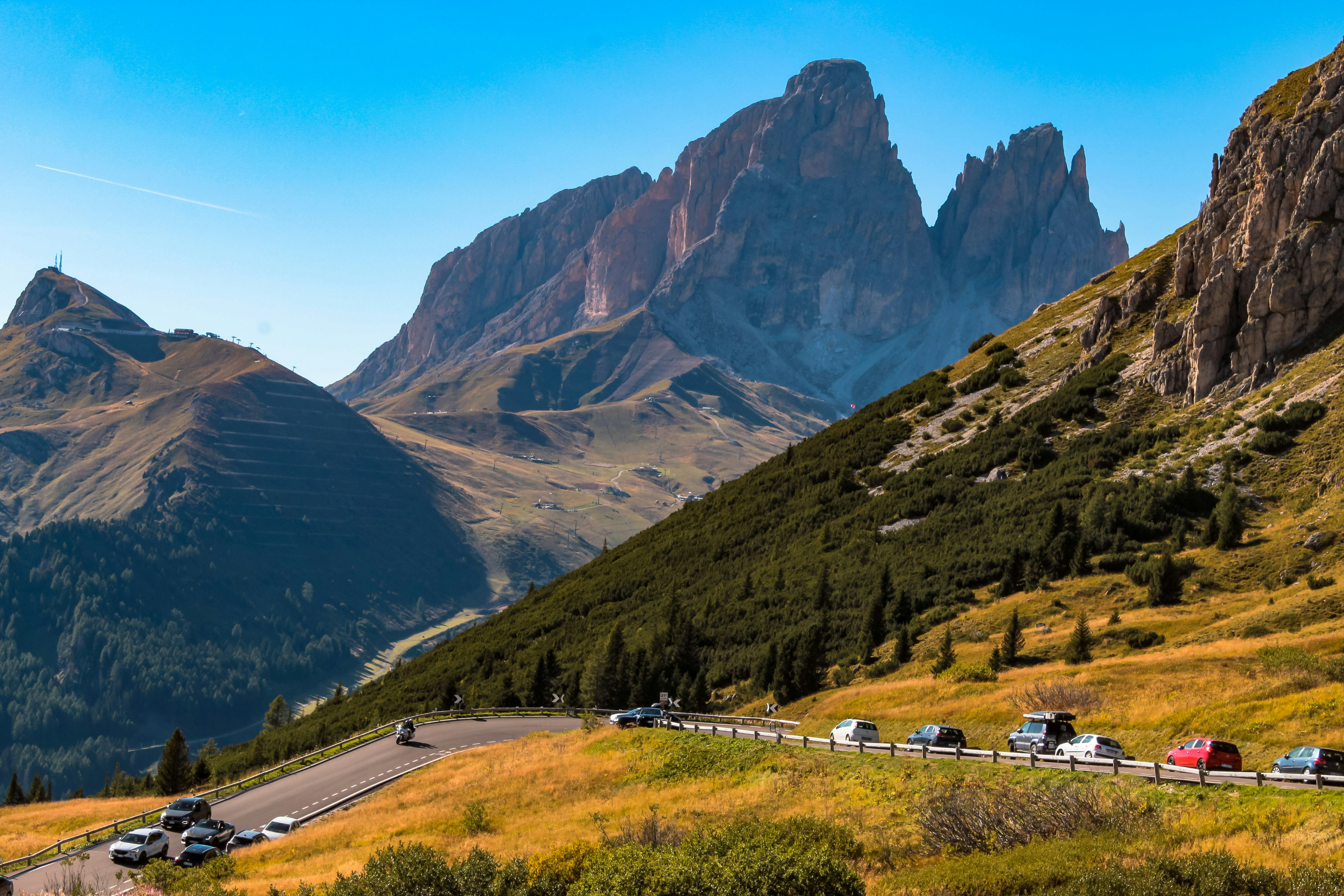 Auto che percorrono una strada di montagna tortuosa sotto le vette frastagliate delle Dolomiti
