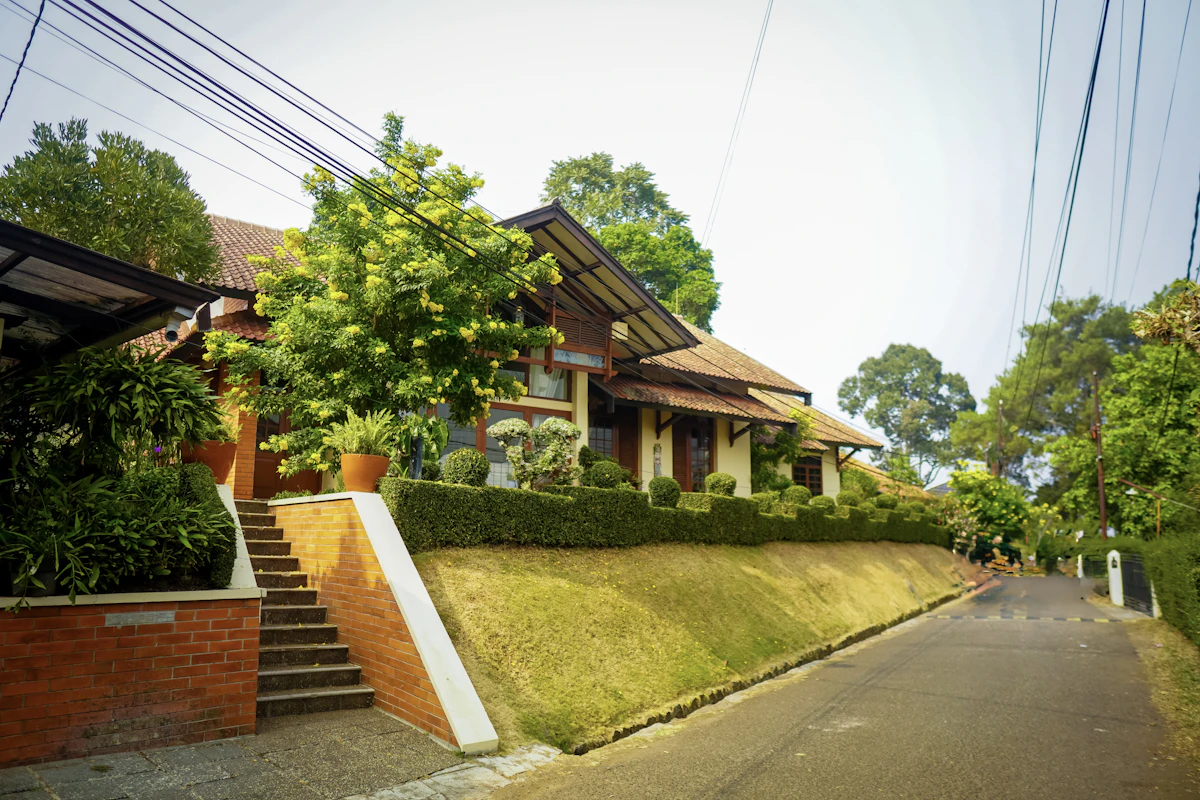 Rumah beratap genteng dengan tangga bata dan taman