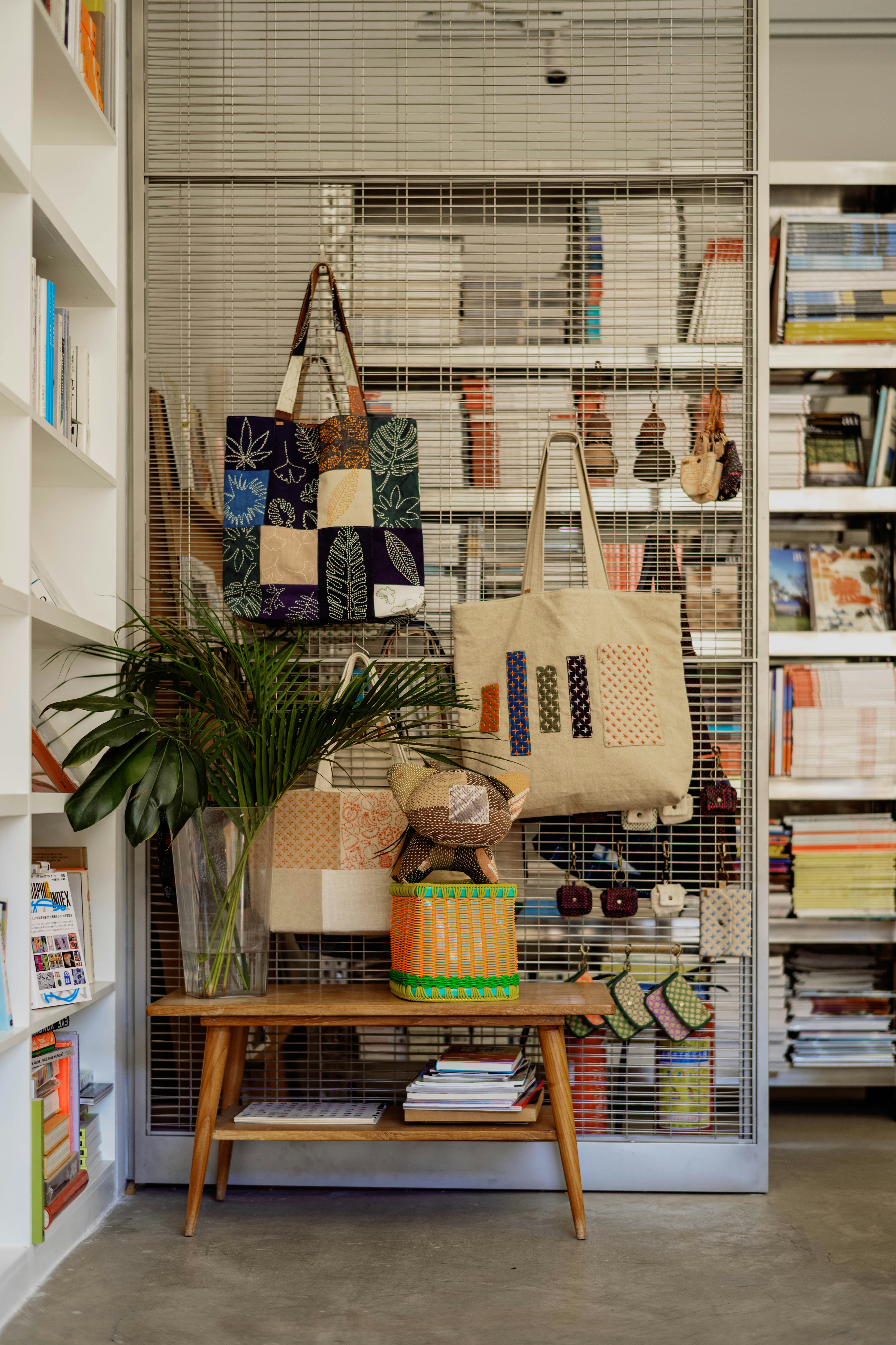 Tote bags and small pouches hanging on a wire grid in a bookstore - 相关推荐