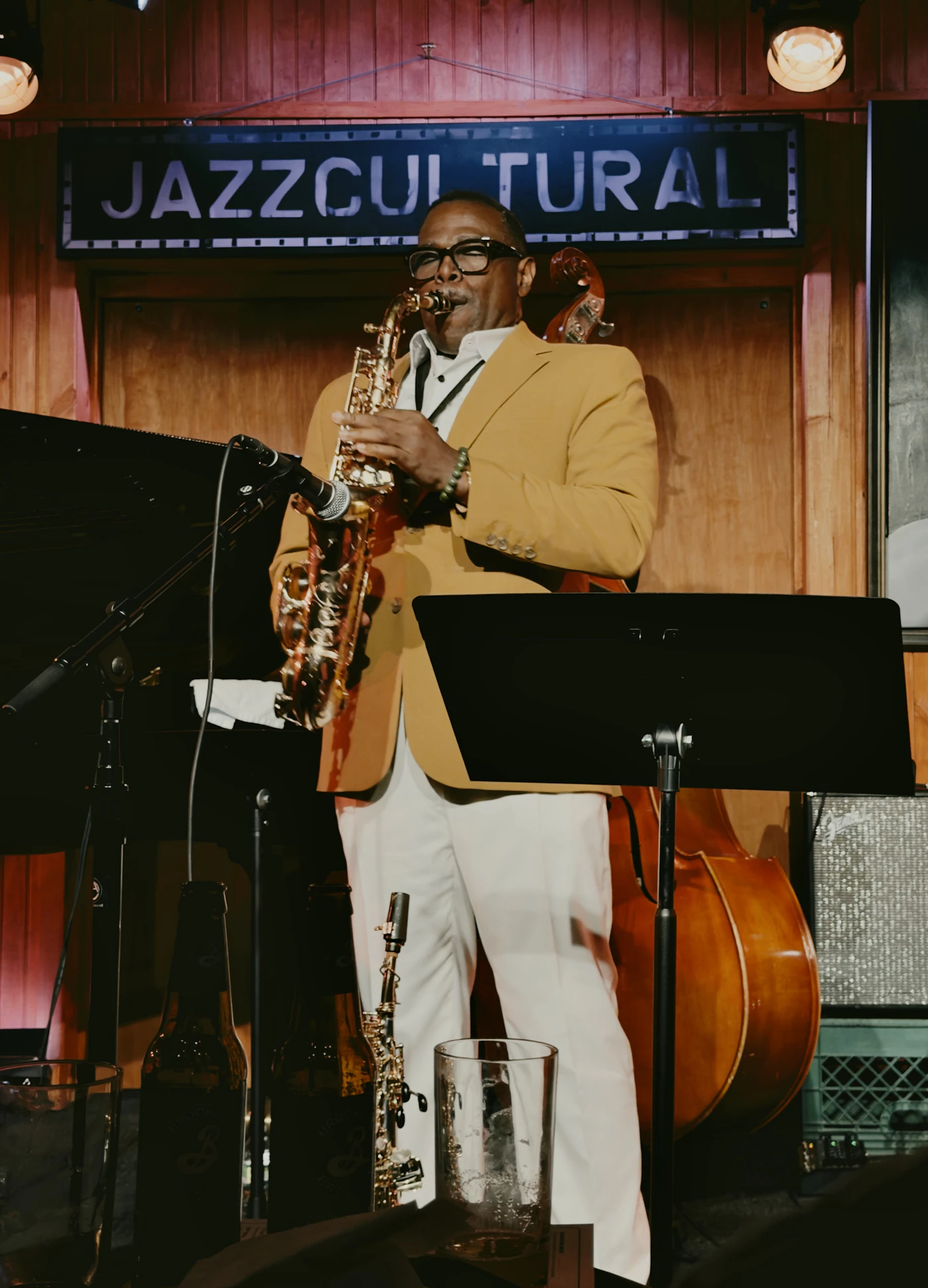 A saxophonist in a mustard blazer on stage with a double bass