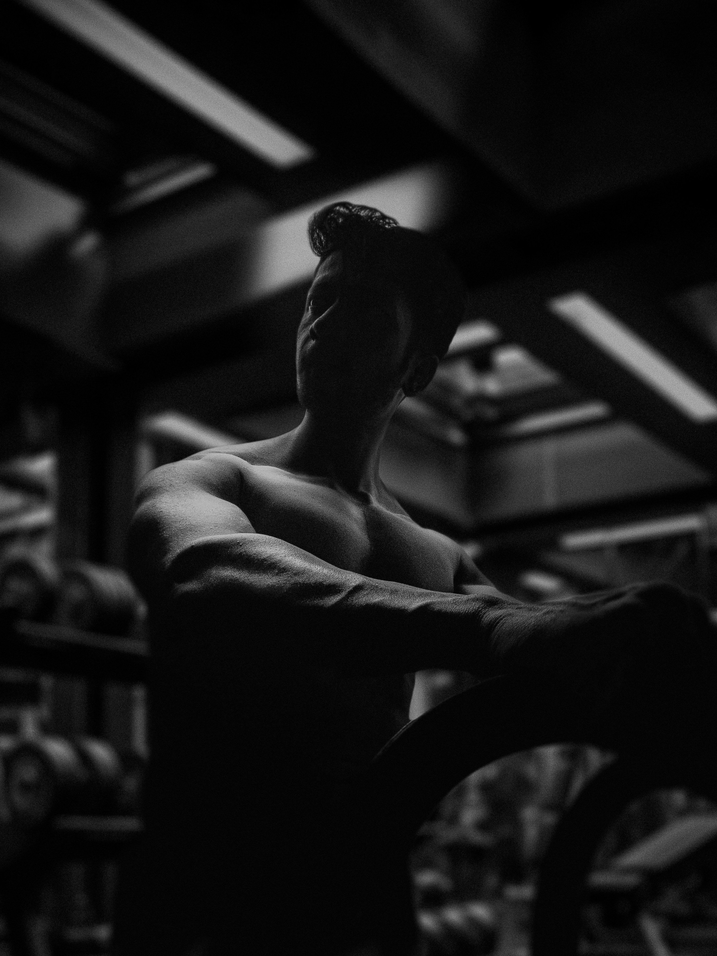 Um homem sem camisa com músculos definidos em uma academia mal iluminada