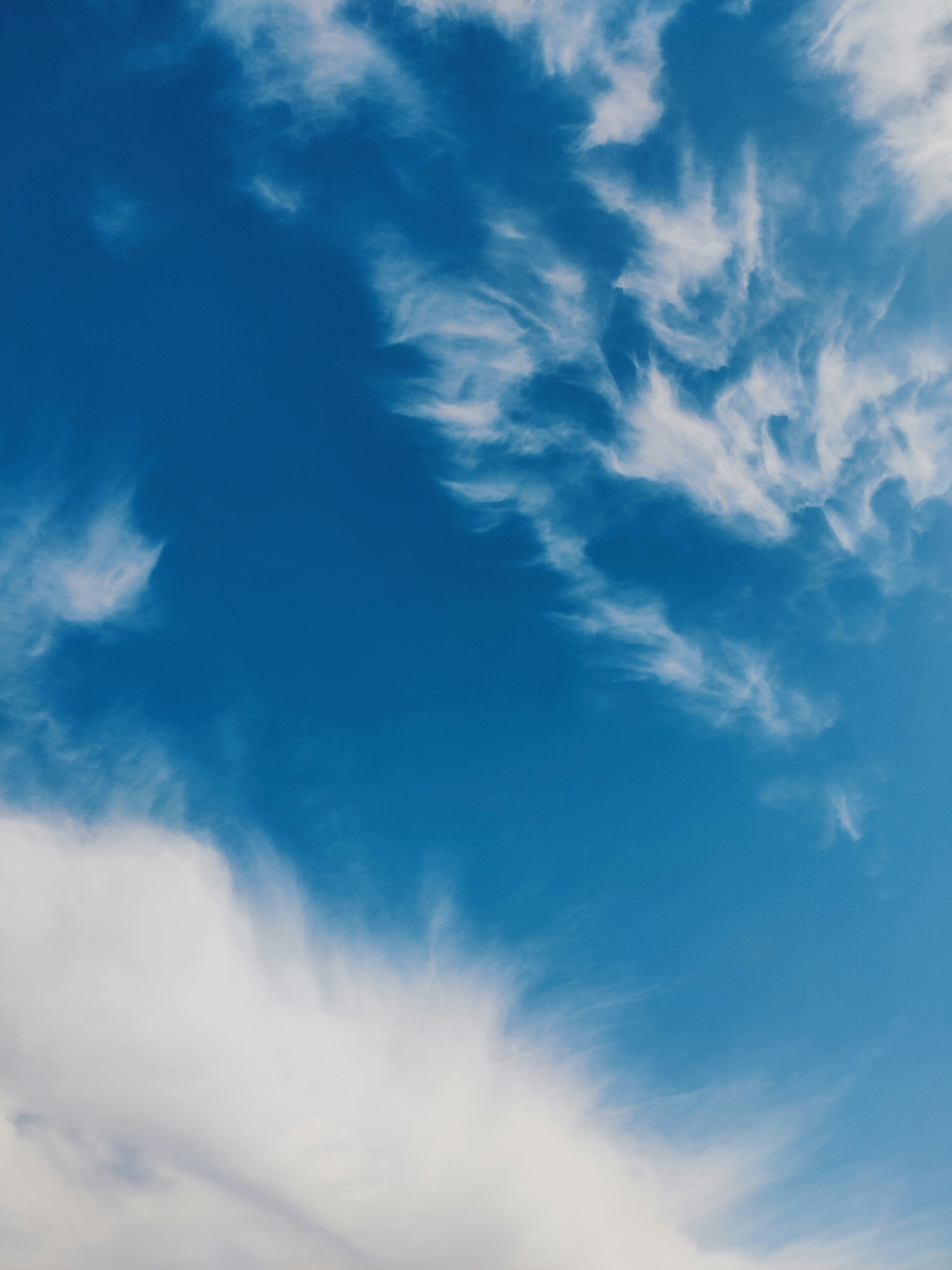 Wispy white cirrus clouds drifting across a bright blue sky