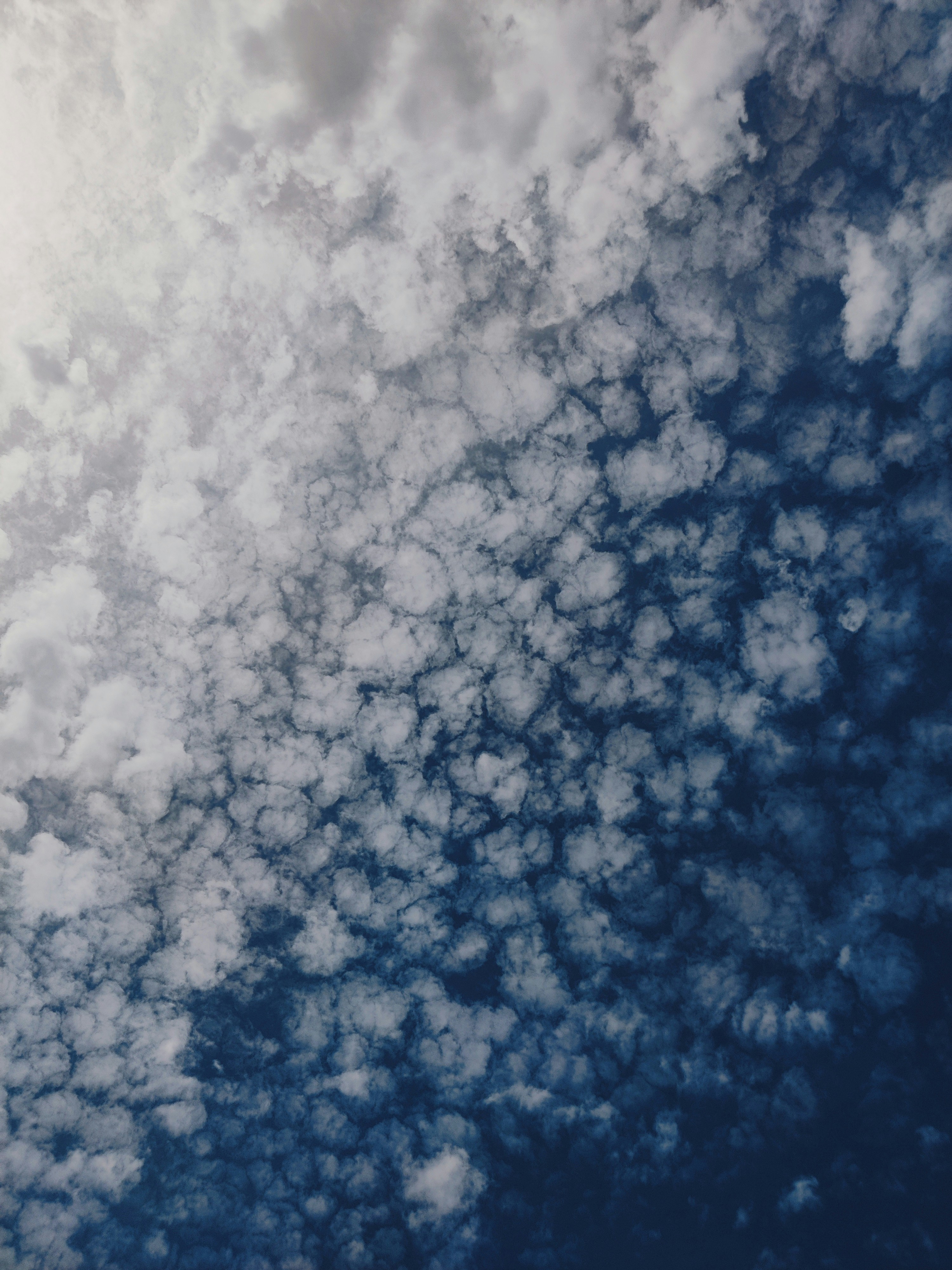 Small white clouds scattered across a deep blue sky with bright light