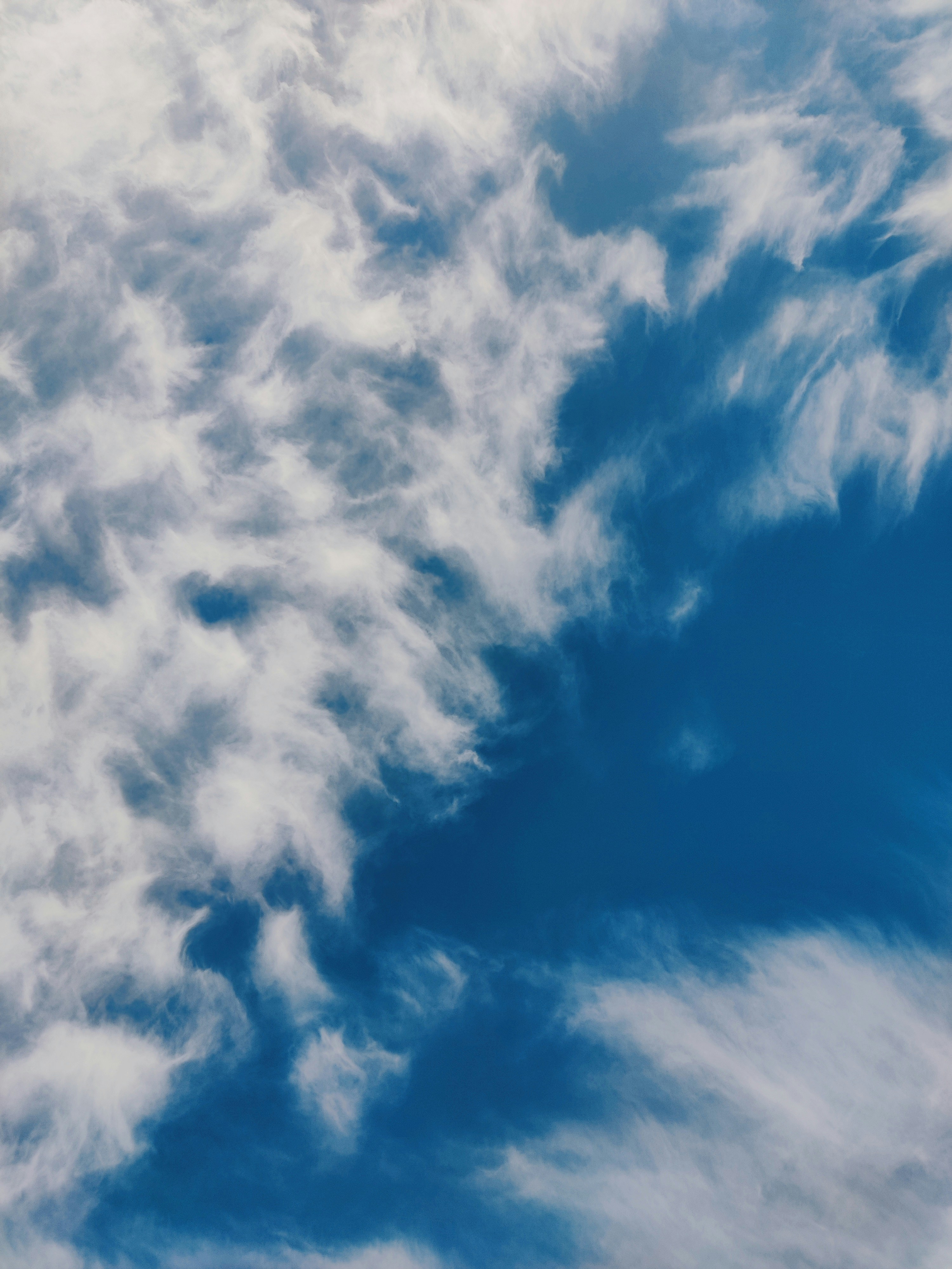 Wispy white cirrus clouds scattered across a deep blue sky