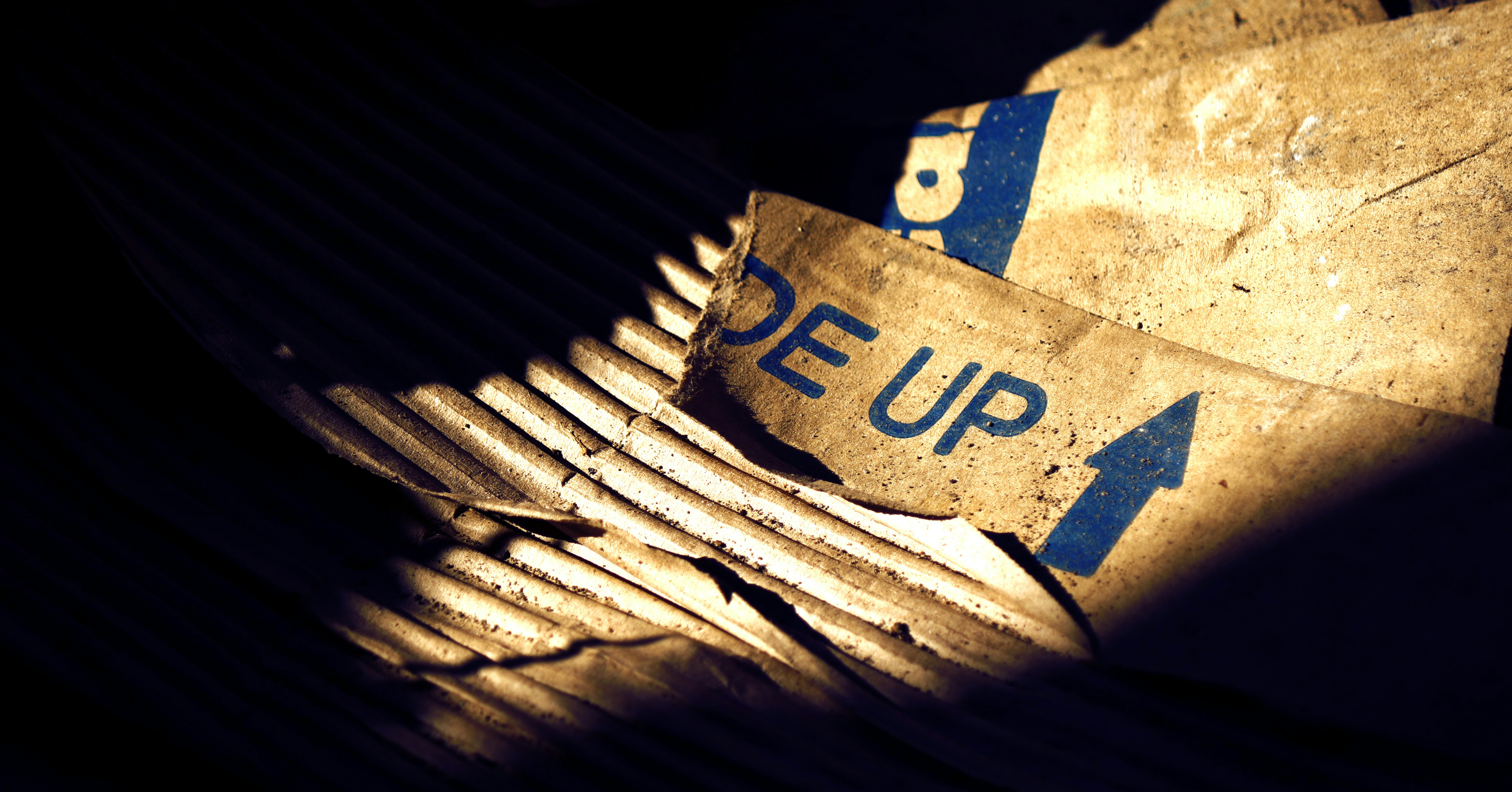 Cartone strappato con il testo DE UP e una freccia blu in condizioni di scarsa illuminazione