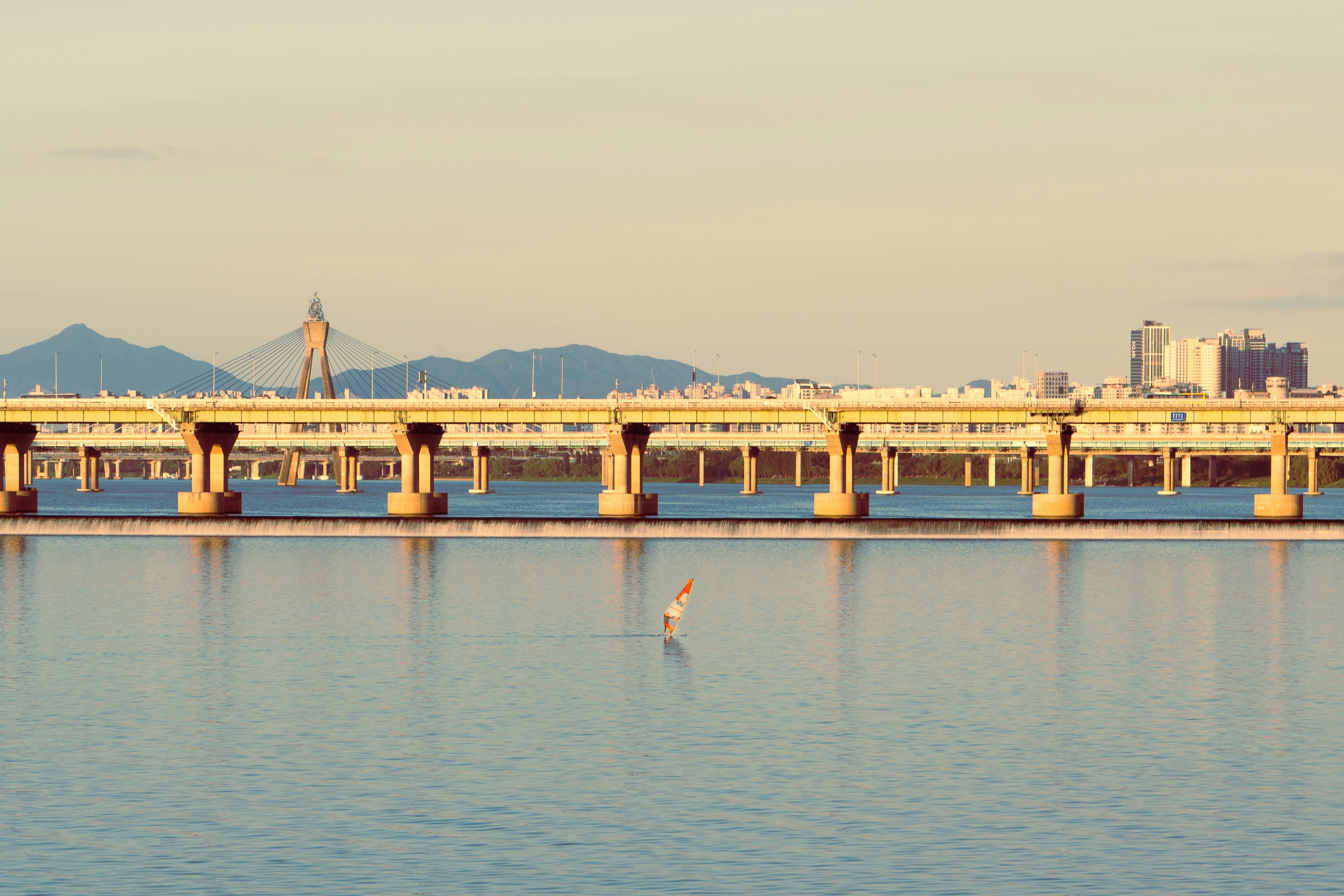 A windsurfer on the Han River with the Banpo Bridge in Seoul