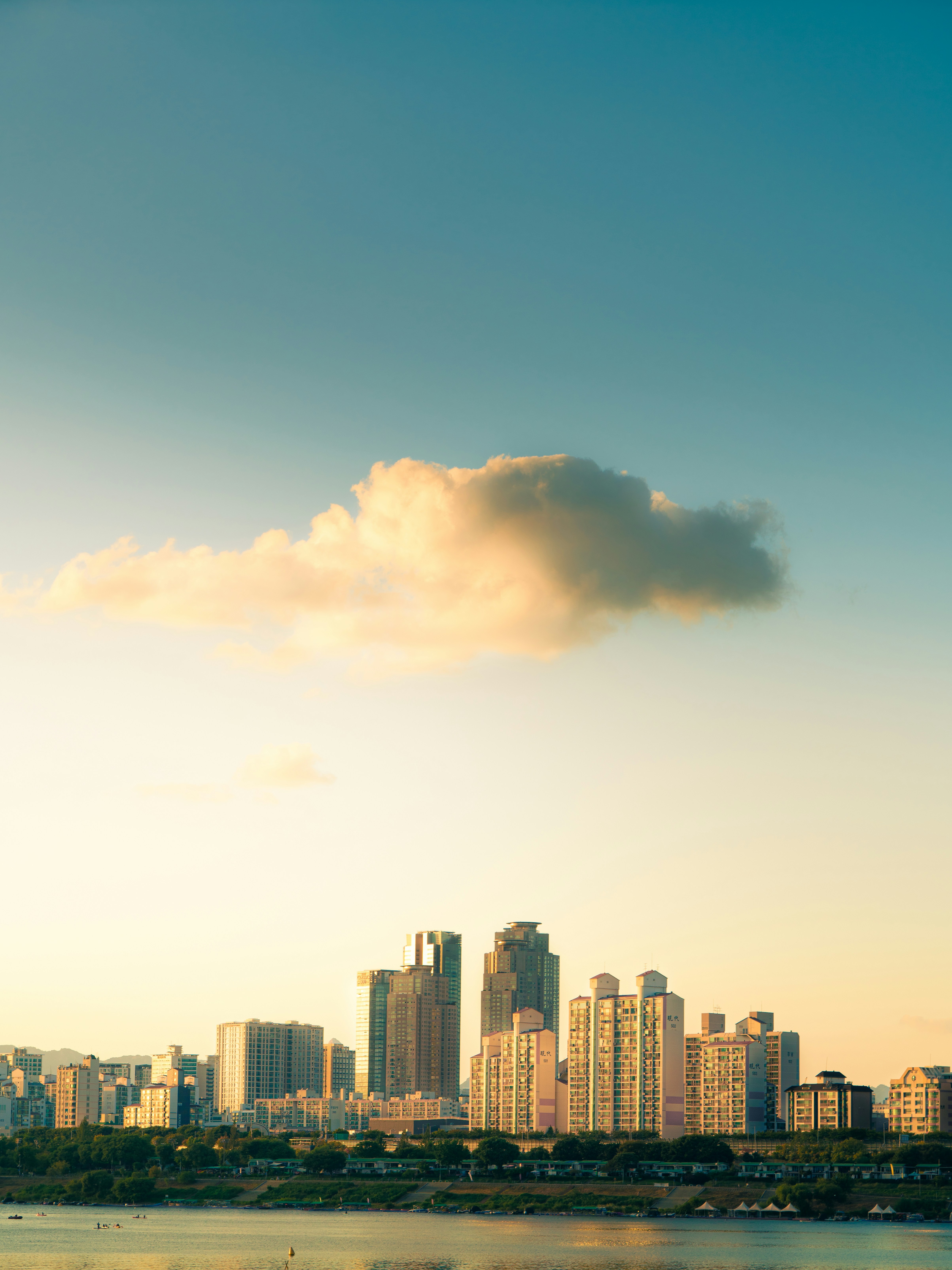 A single cloud glowing in golden light above a city skyline and river