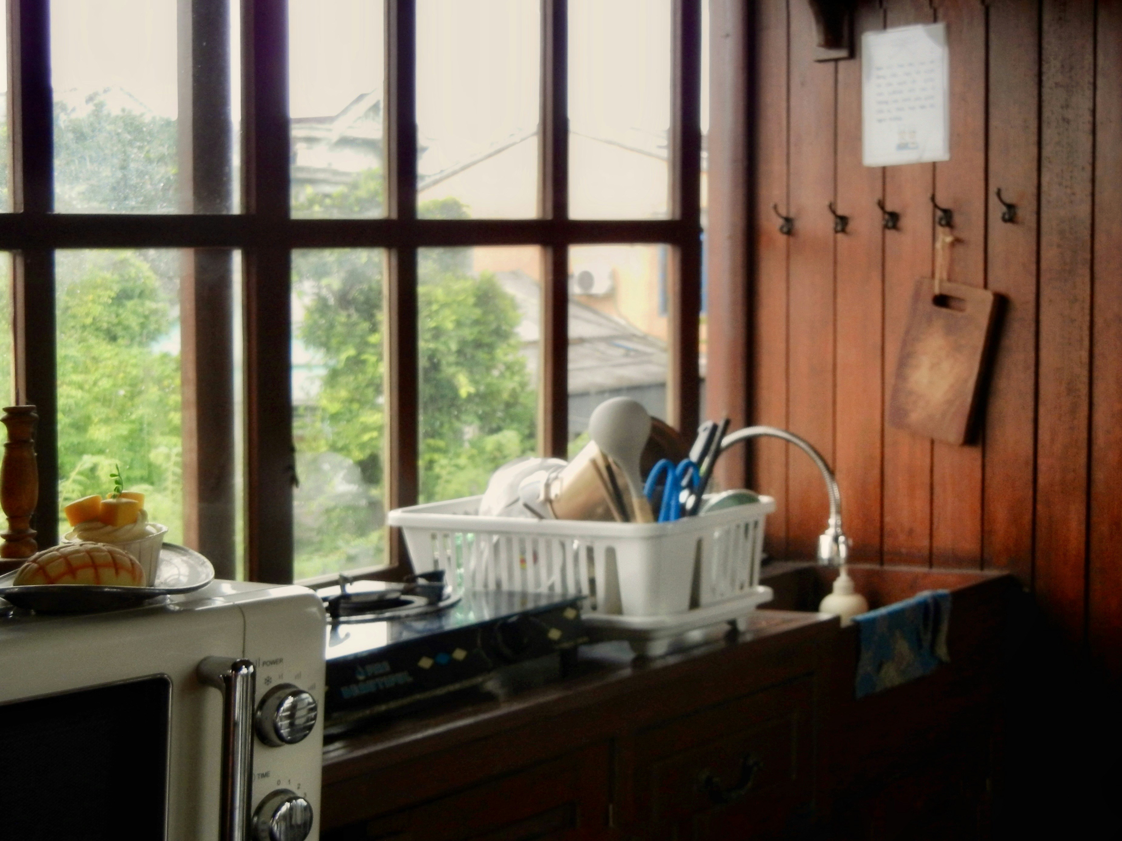 Microwave putih dan rak piring di atas meja kayu di dapur