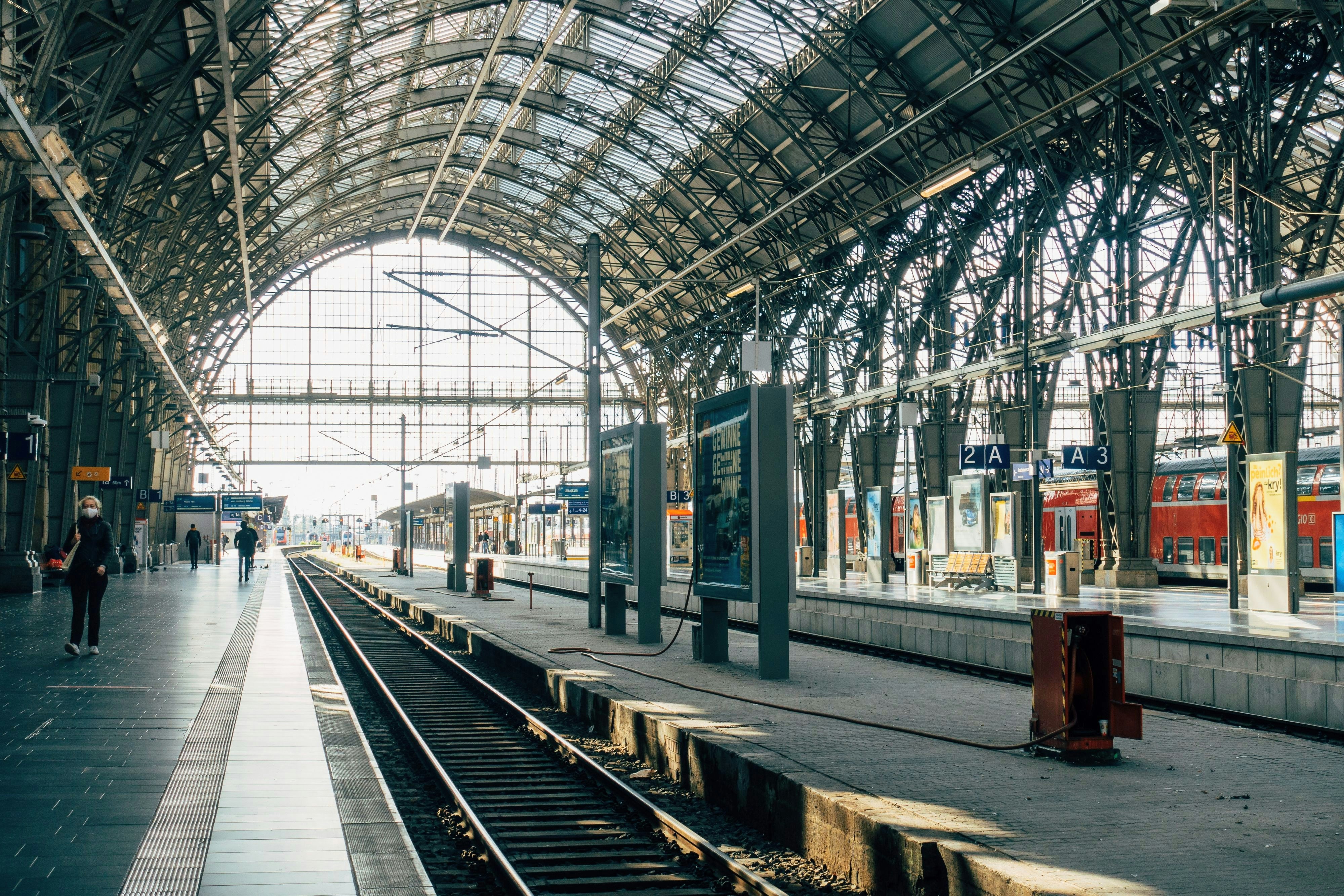 Person walking along a platform under an arched glass roof