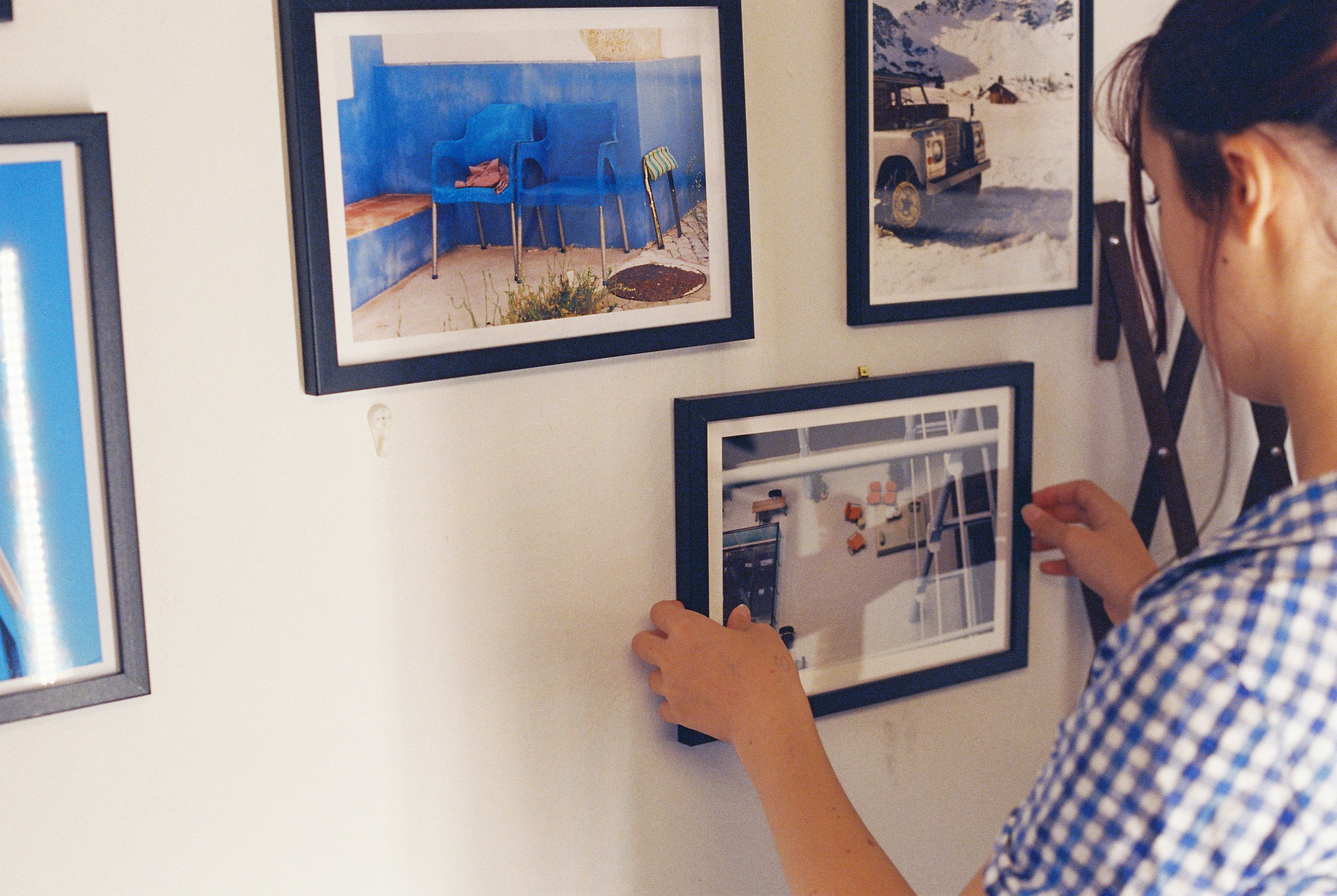 A woman adjusting a framed picture on a wall