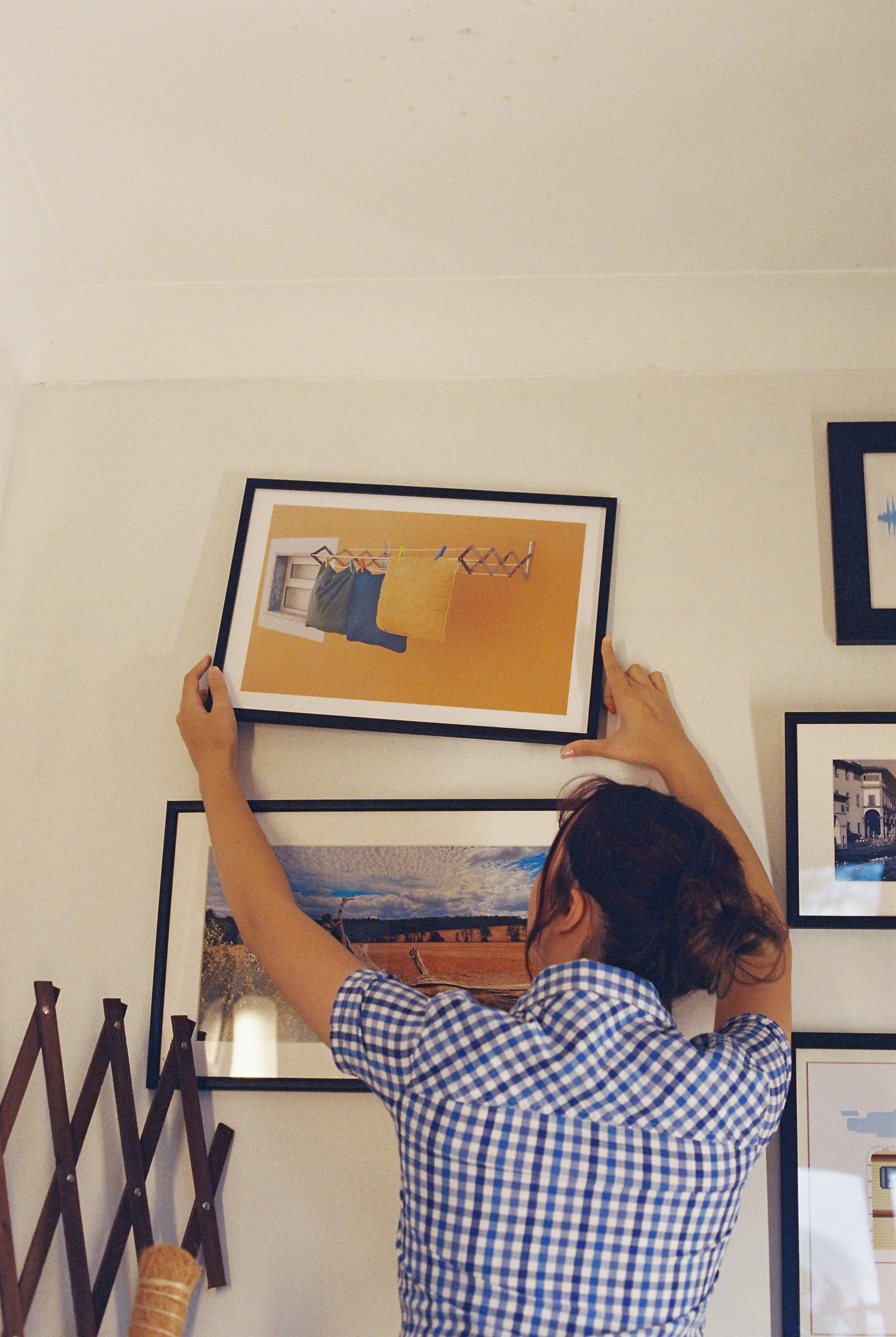 A woman hanging a framed picture on a wall