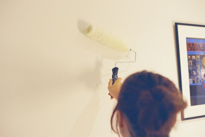 Mulher pintando parede com rolo