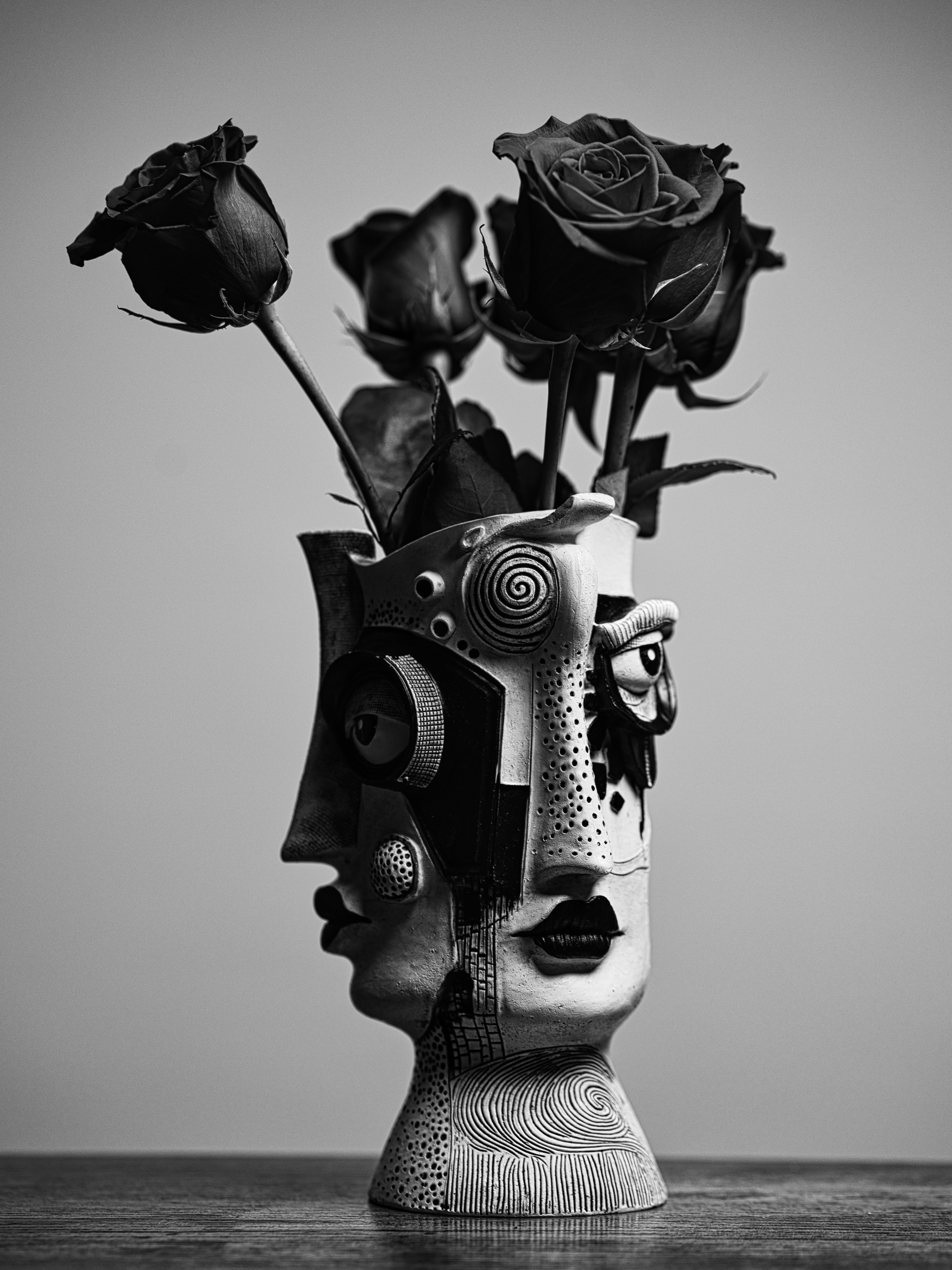 Rosas en un jarrón de cerámica con forma de rostro con patrones abstractos