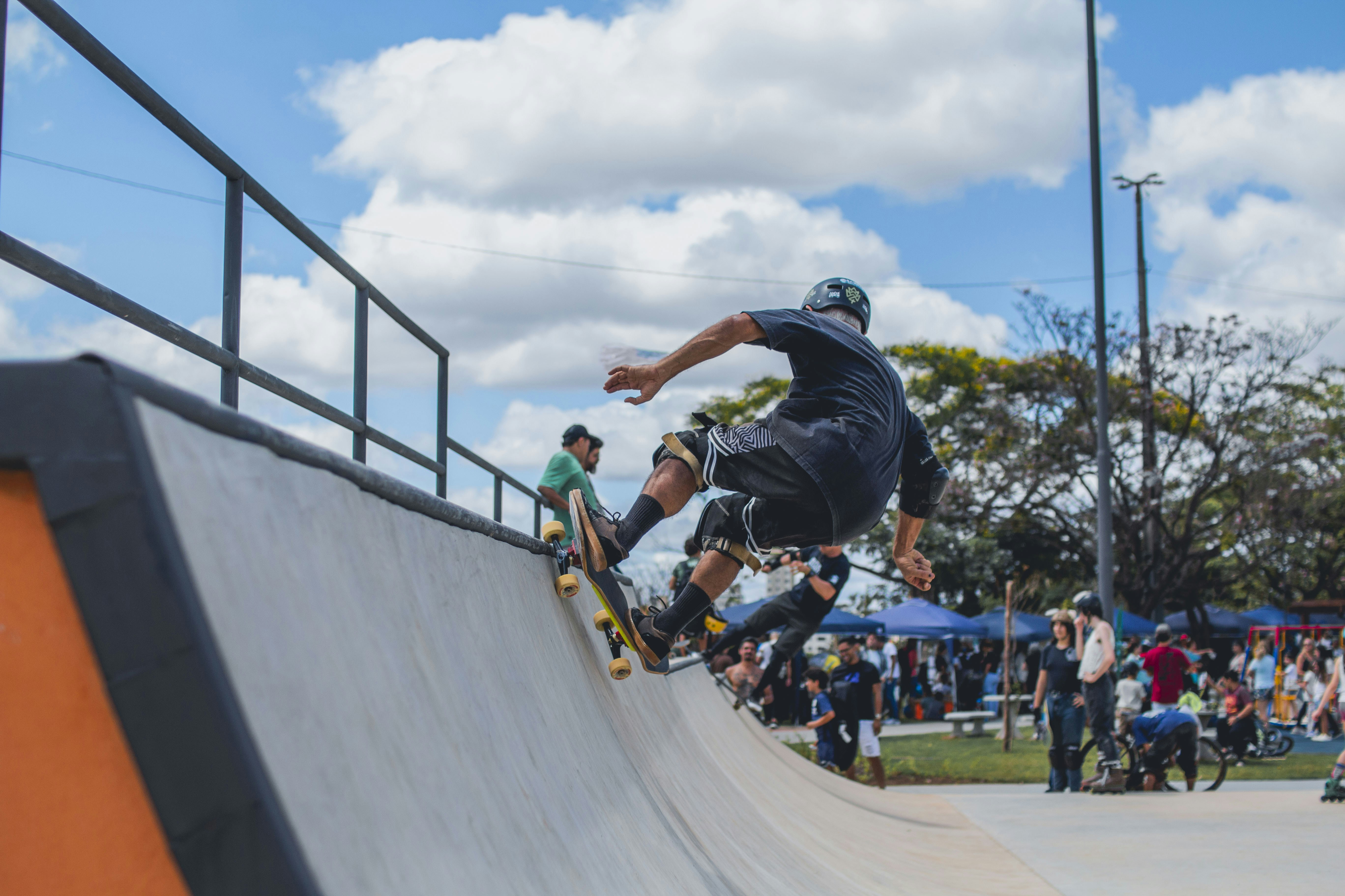 A skateboarder performing a trick on a concrete ramp at a sunny park