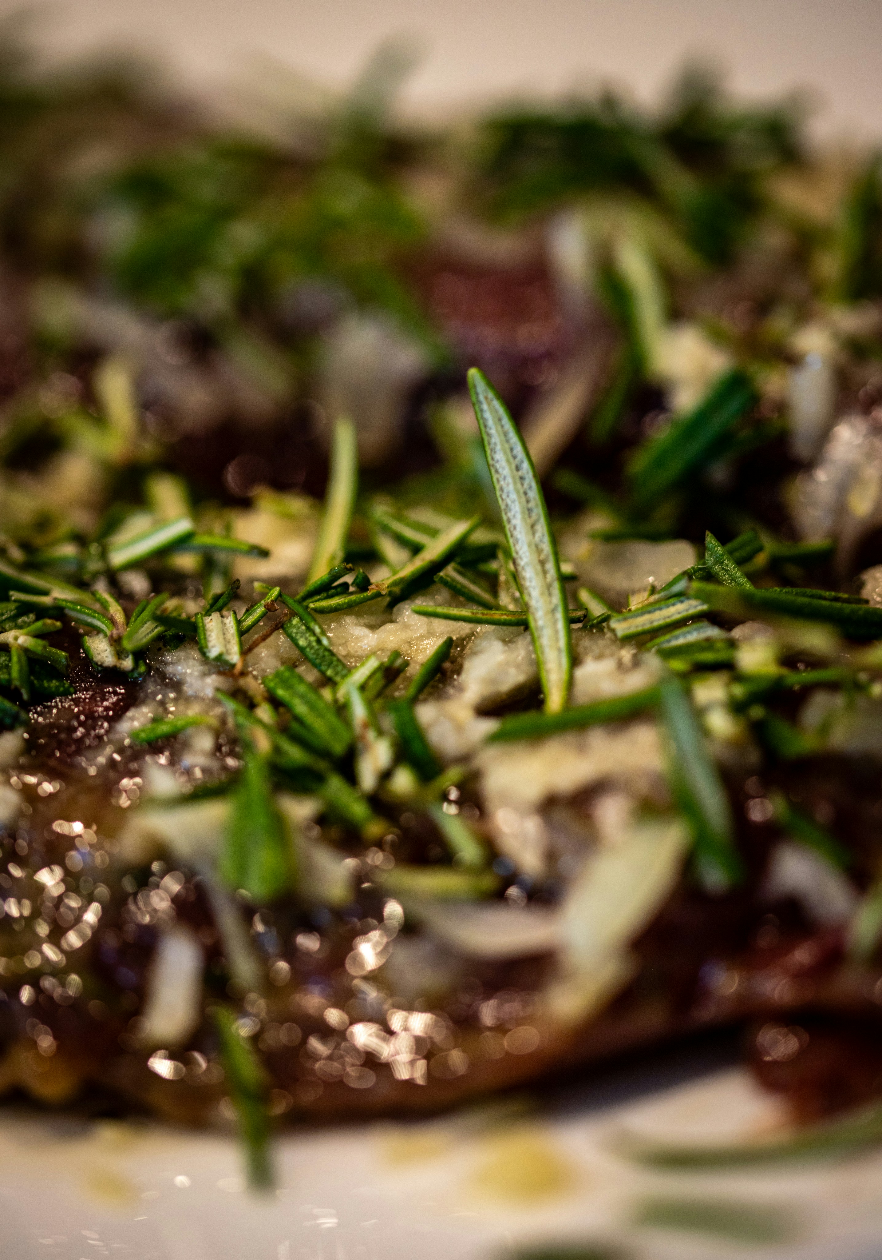 Fresh rosemary needles and minced garlic sprinkled over a dark cooked meat dish