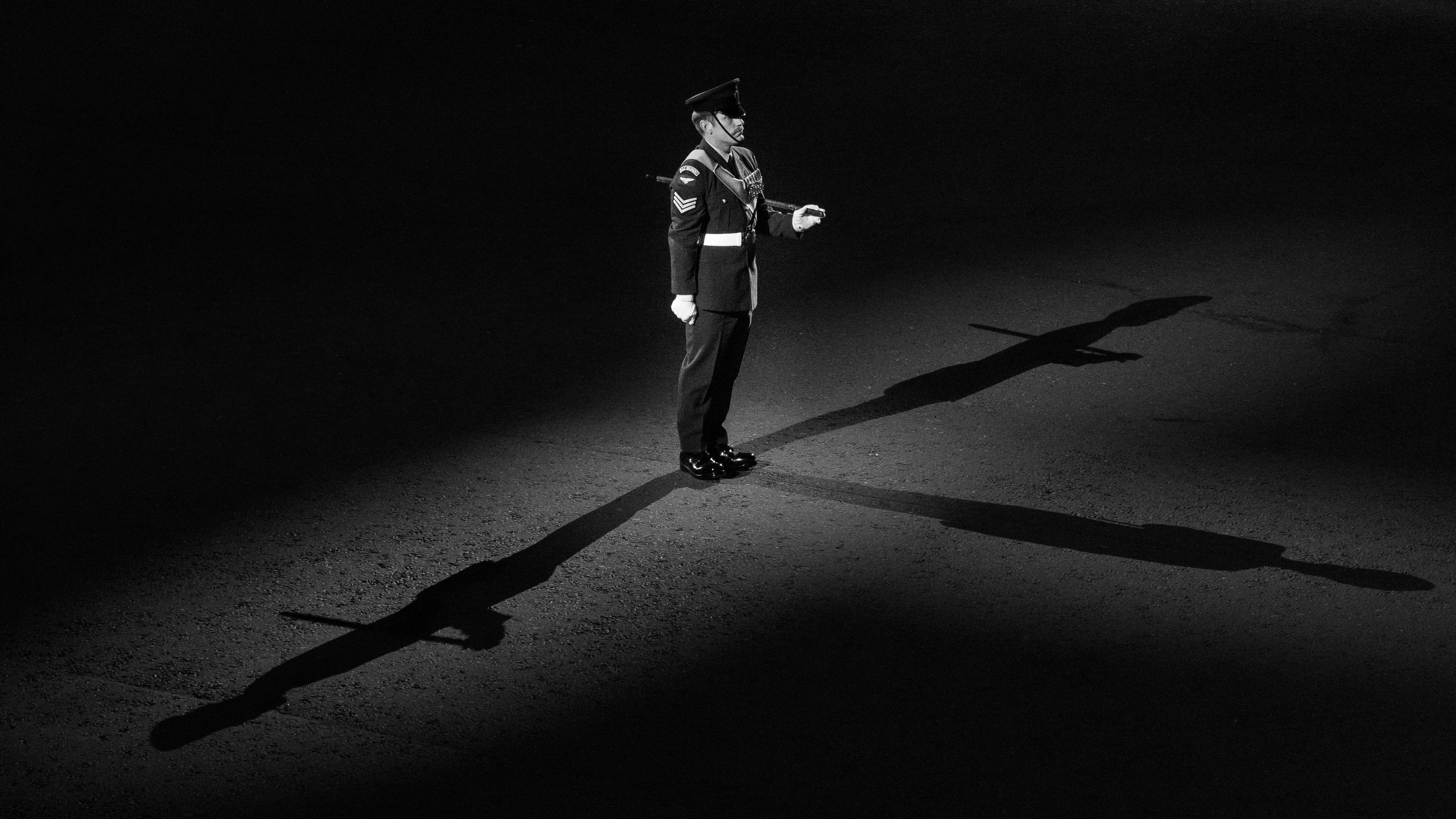 A soldier in uniform with long shadows cast on the ground