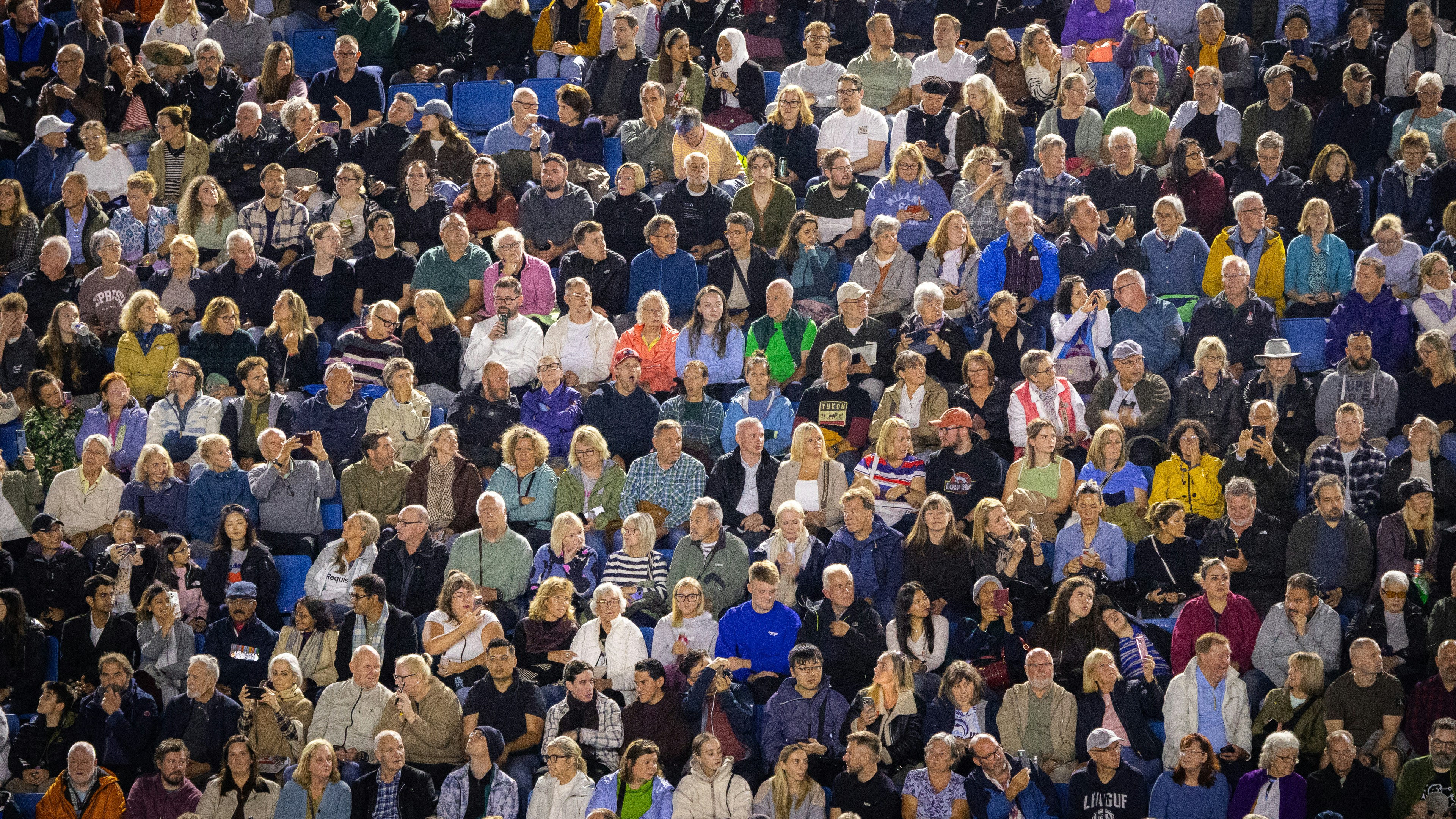 A large crowd of people sitting in stadium seating at an evening event
