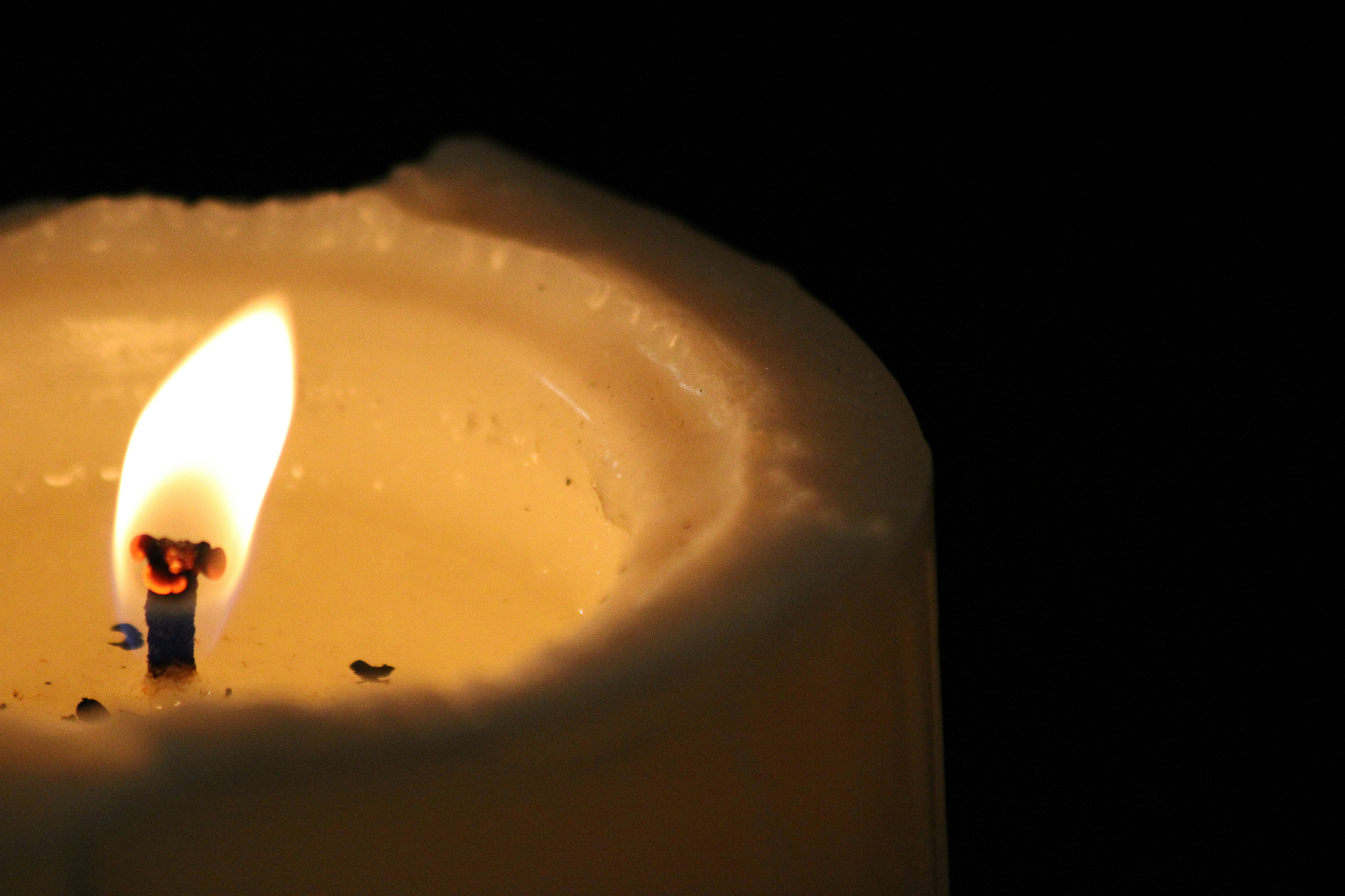 A single lit candle with a glowing flame against a dark background