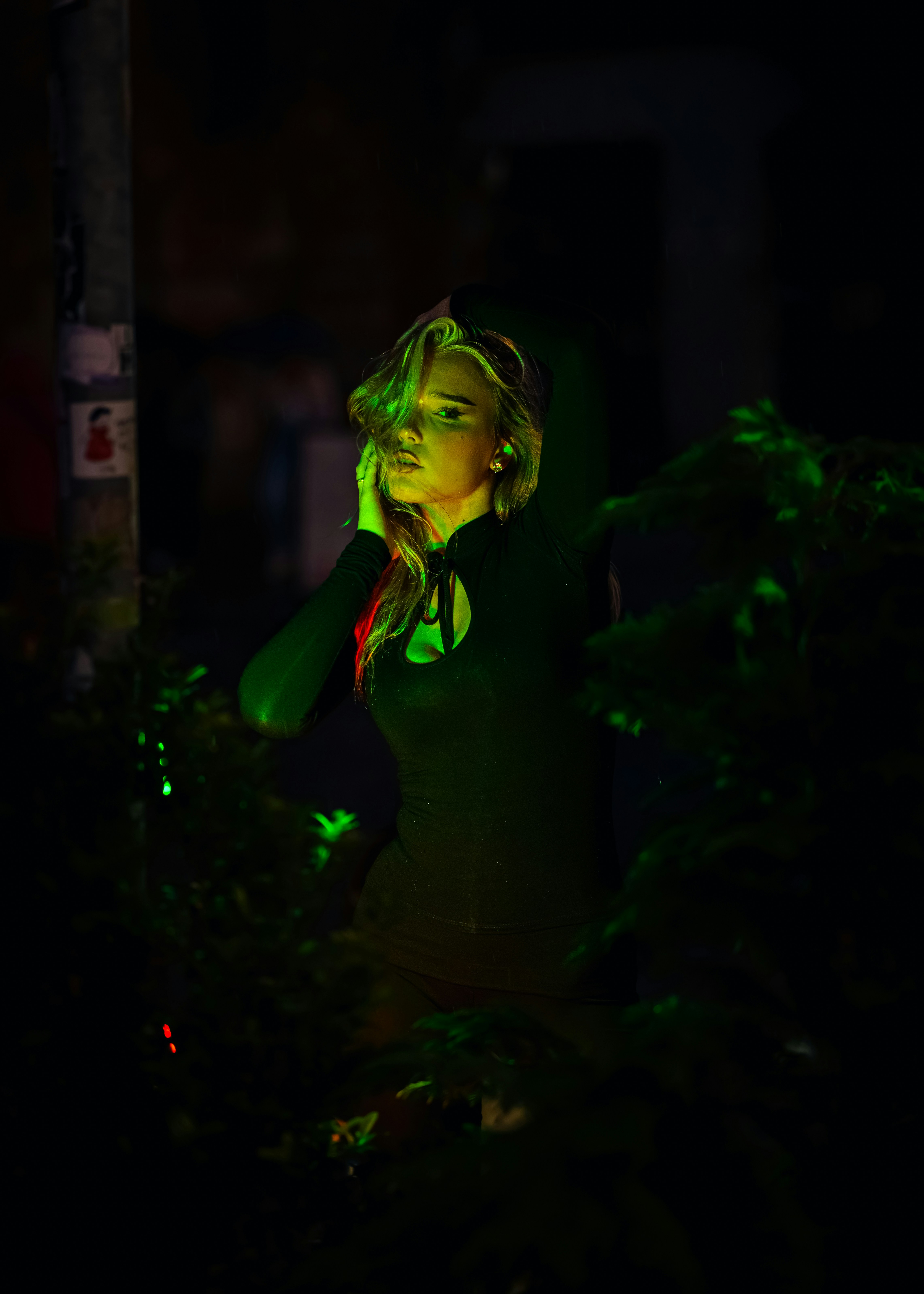 A woman in a black long-sleeved top illuminated by vibrant green light at night