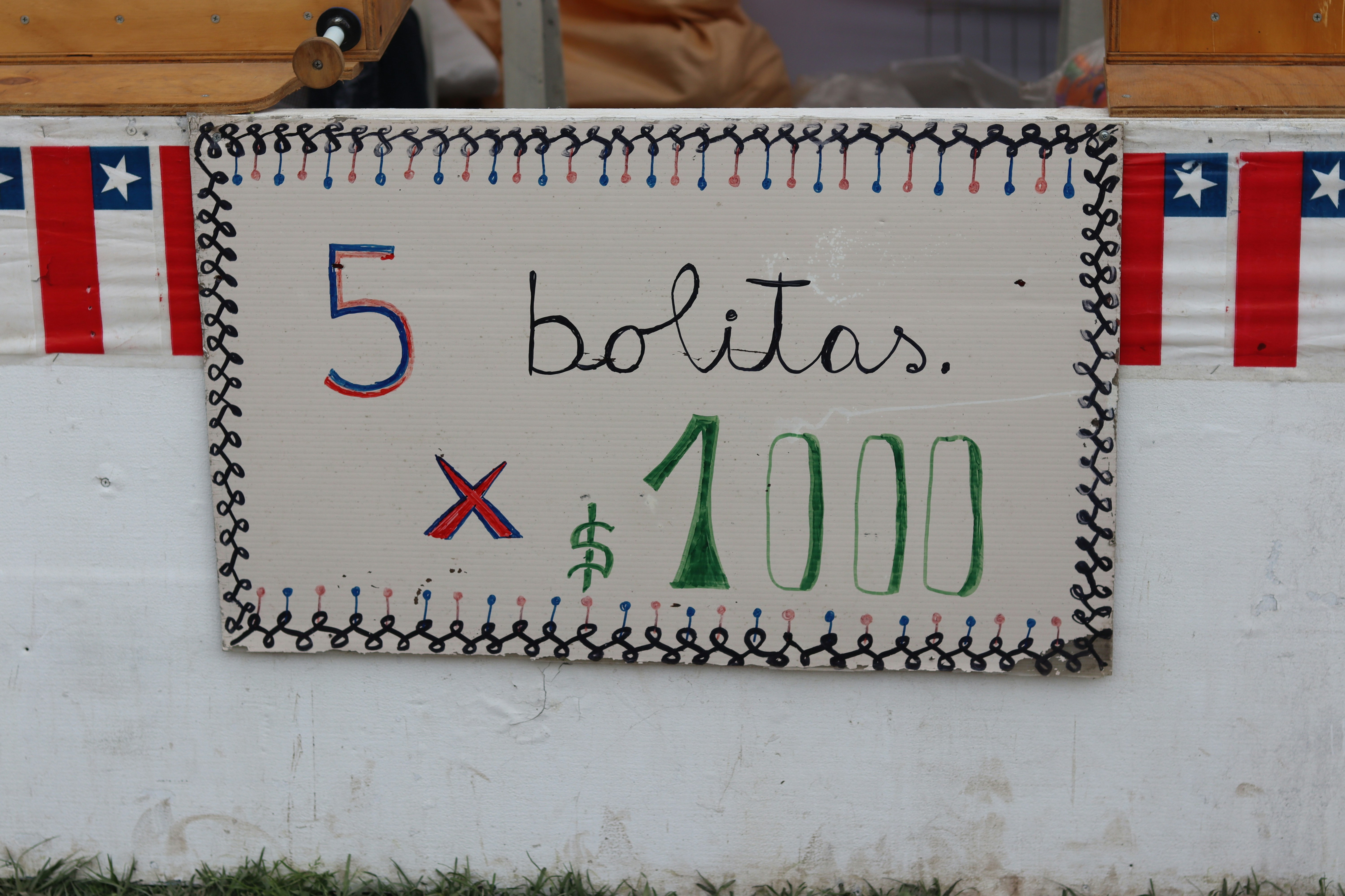 A hand-painted sign reading 5 bolitas x 1000 on a white surface