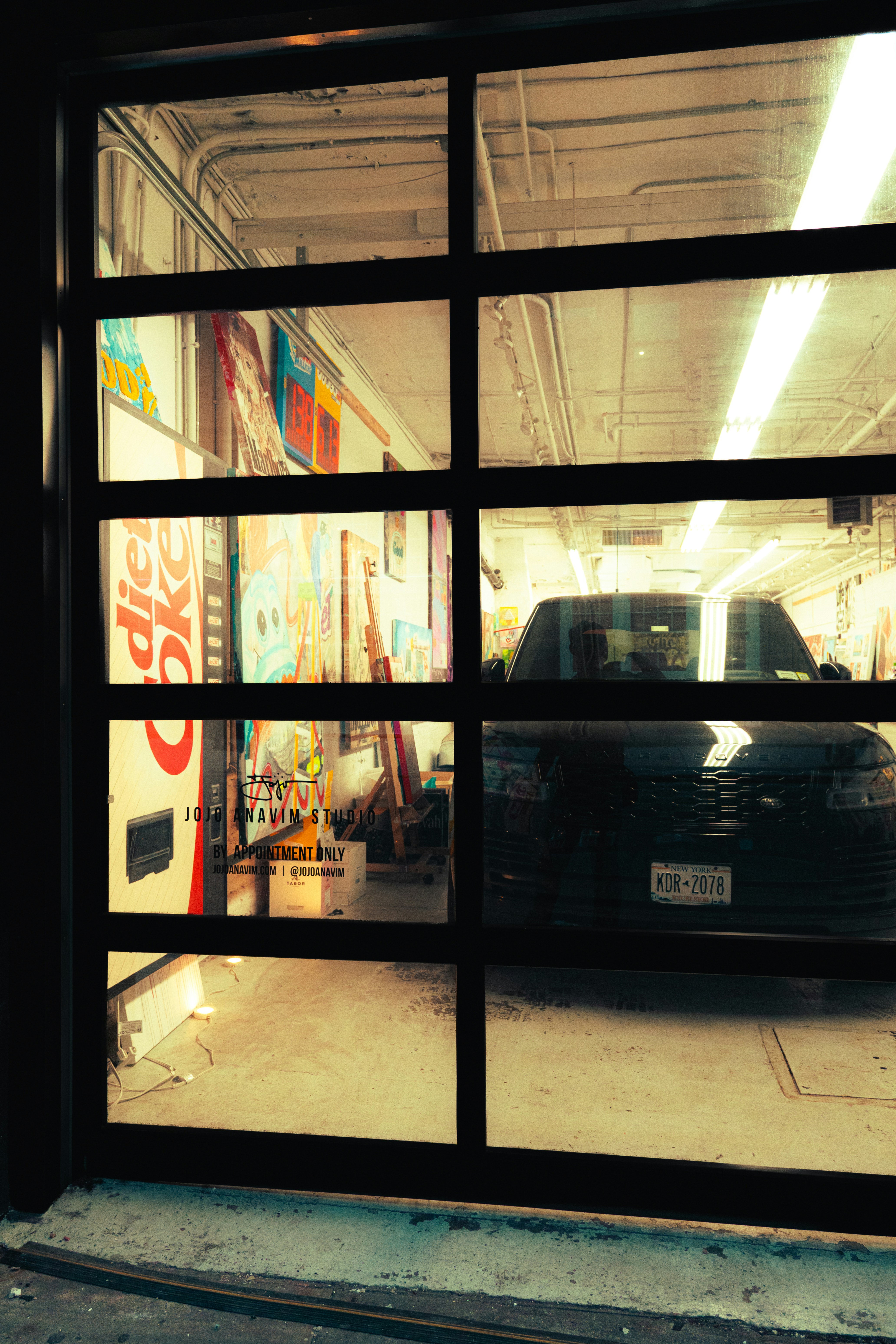 Lit full-view glass garage door at night awaiting 24/7 emergency garage door repair in Palm Desert CA