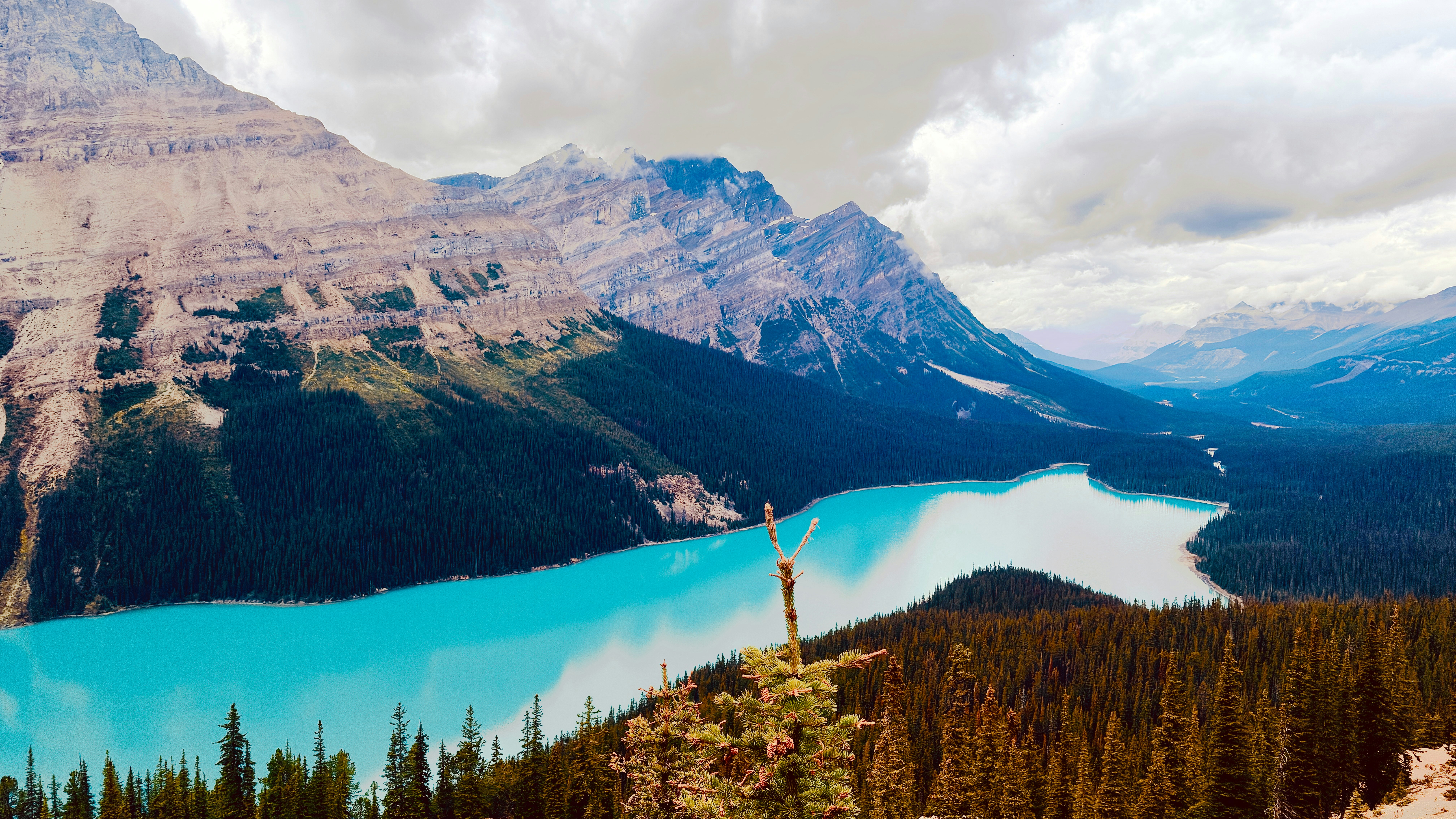 Turquoise glacial lake surrounded by dense pine forests and rugged mountain peaks