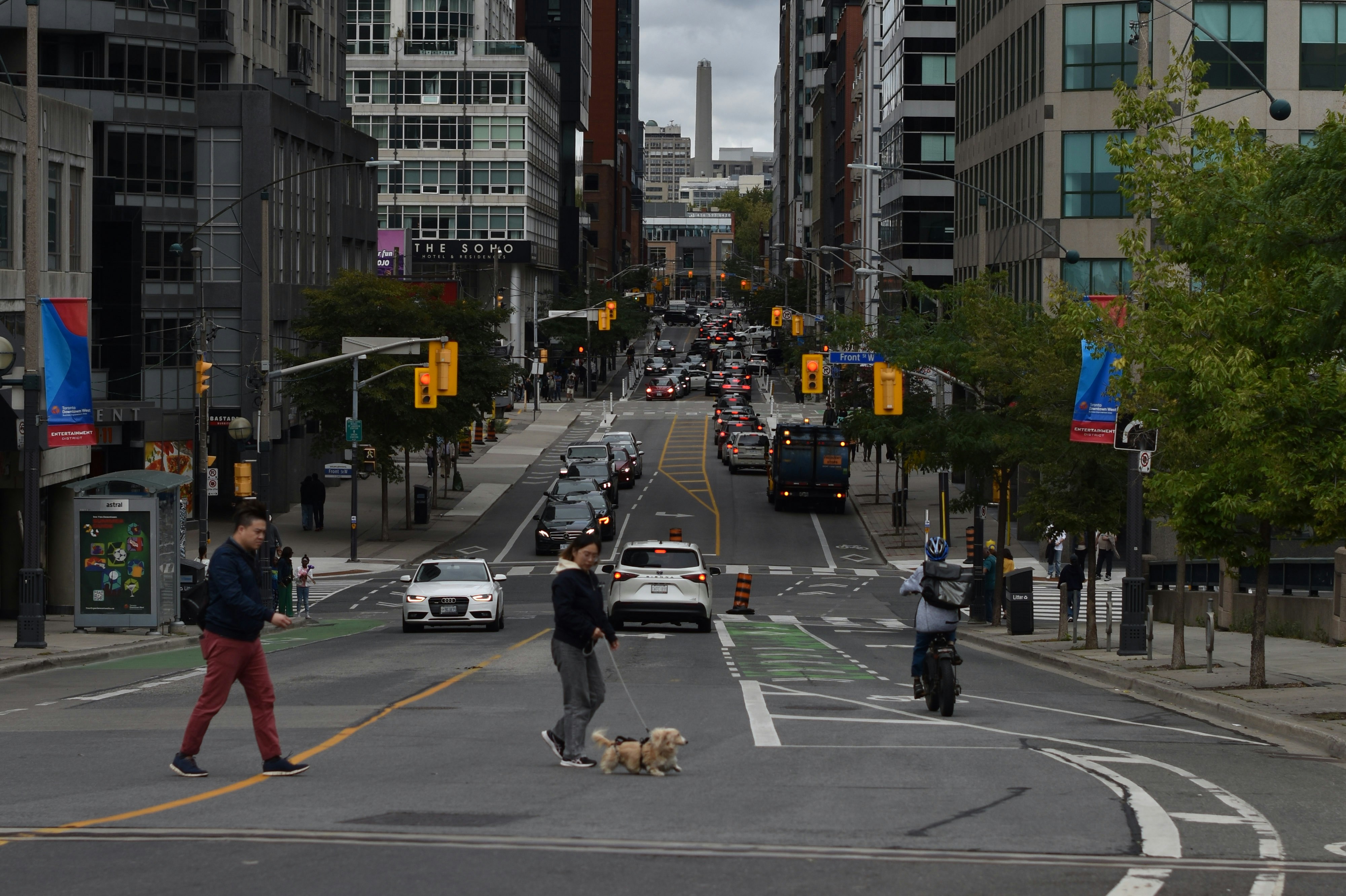 People crossing a busy city street with a bike lane