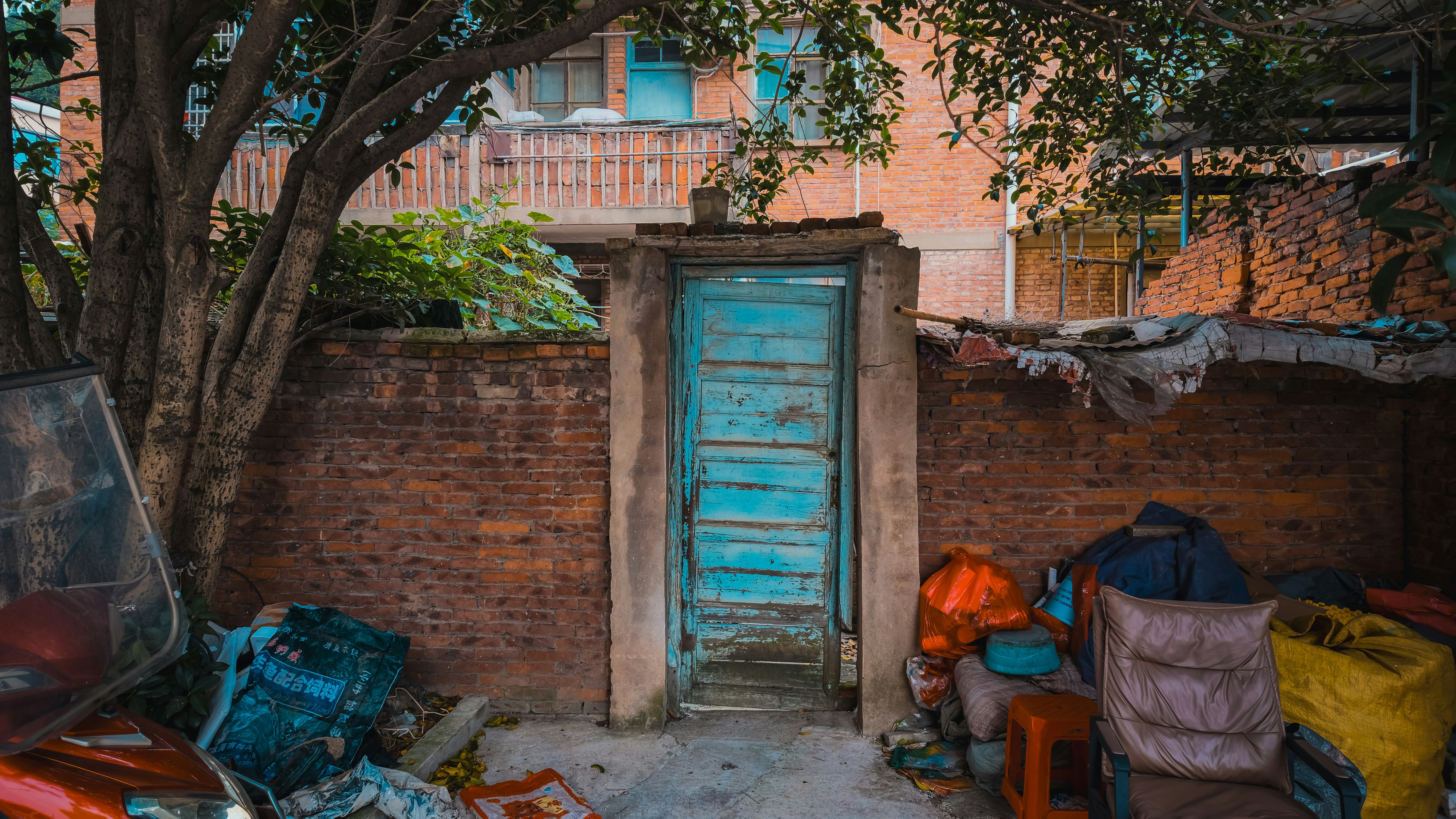 A weathered blue wooden door set into a red brick wall with debris