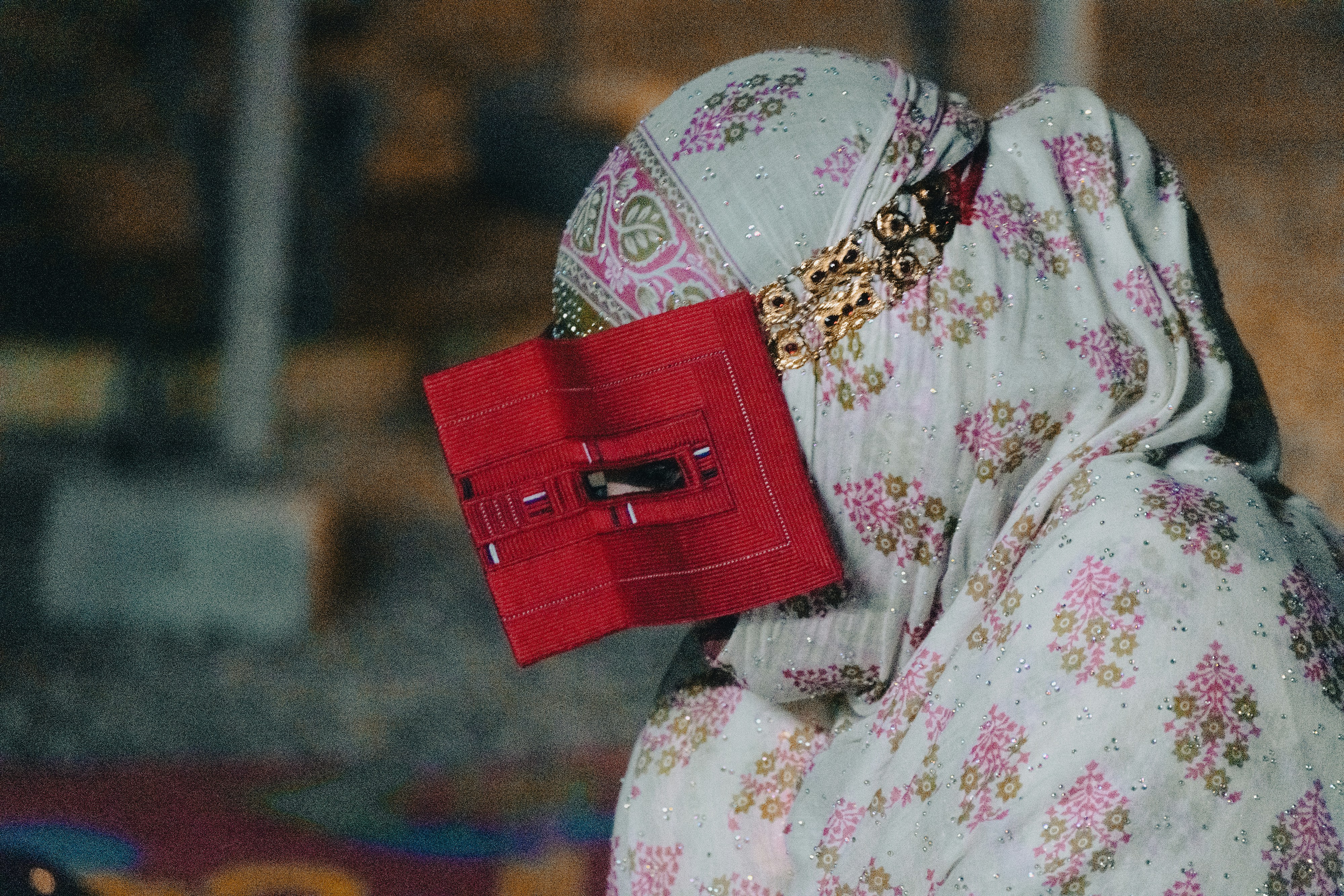 A person wearing a patterned headscarf and a red rectangular face covering