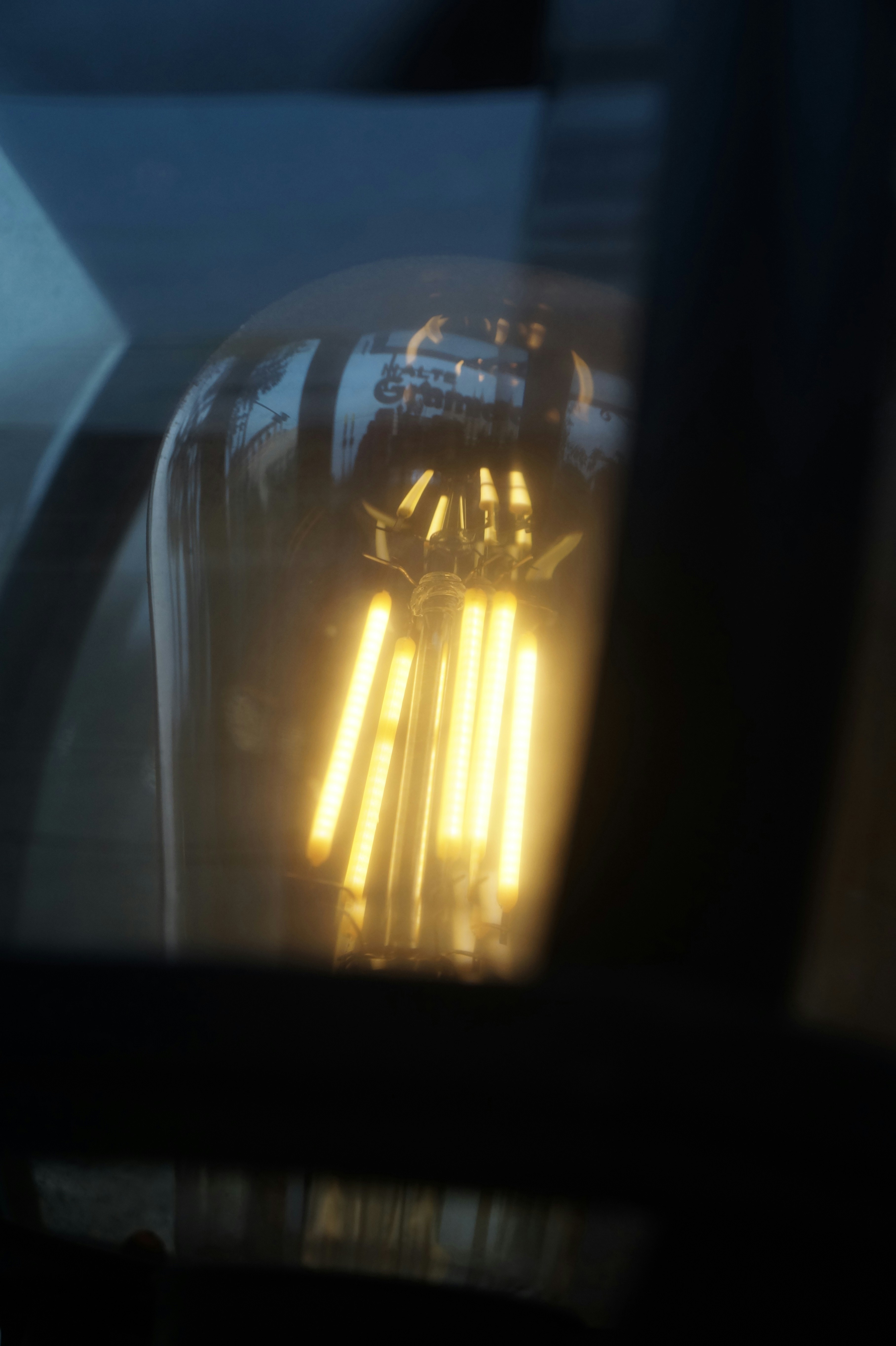A glowing vintage filament light bulb inside a dark glass enclosure