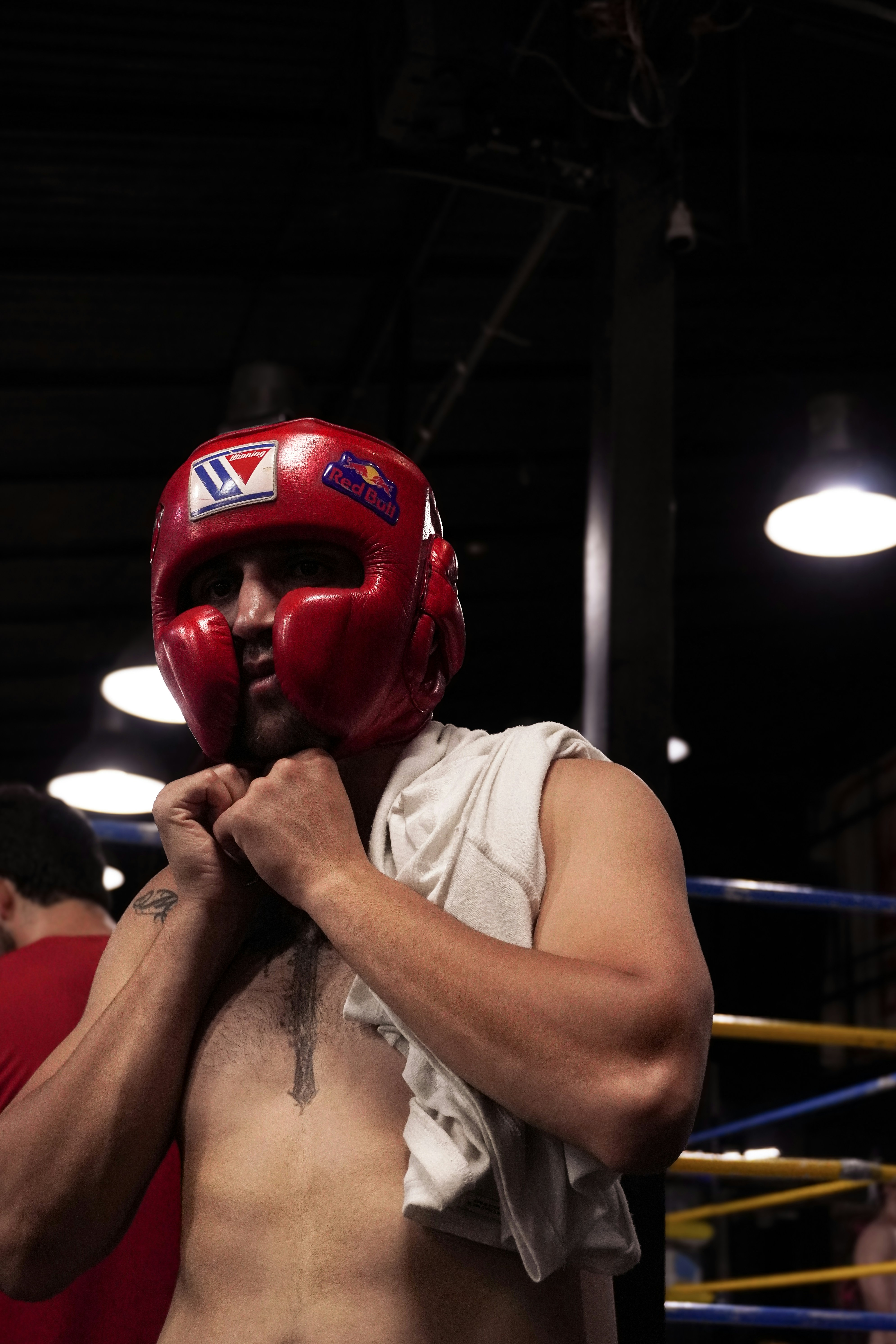 A person wearing a red boxing headgear with a white towel over their shoulder