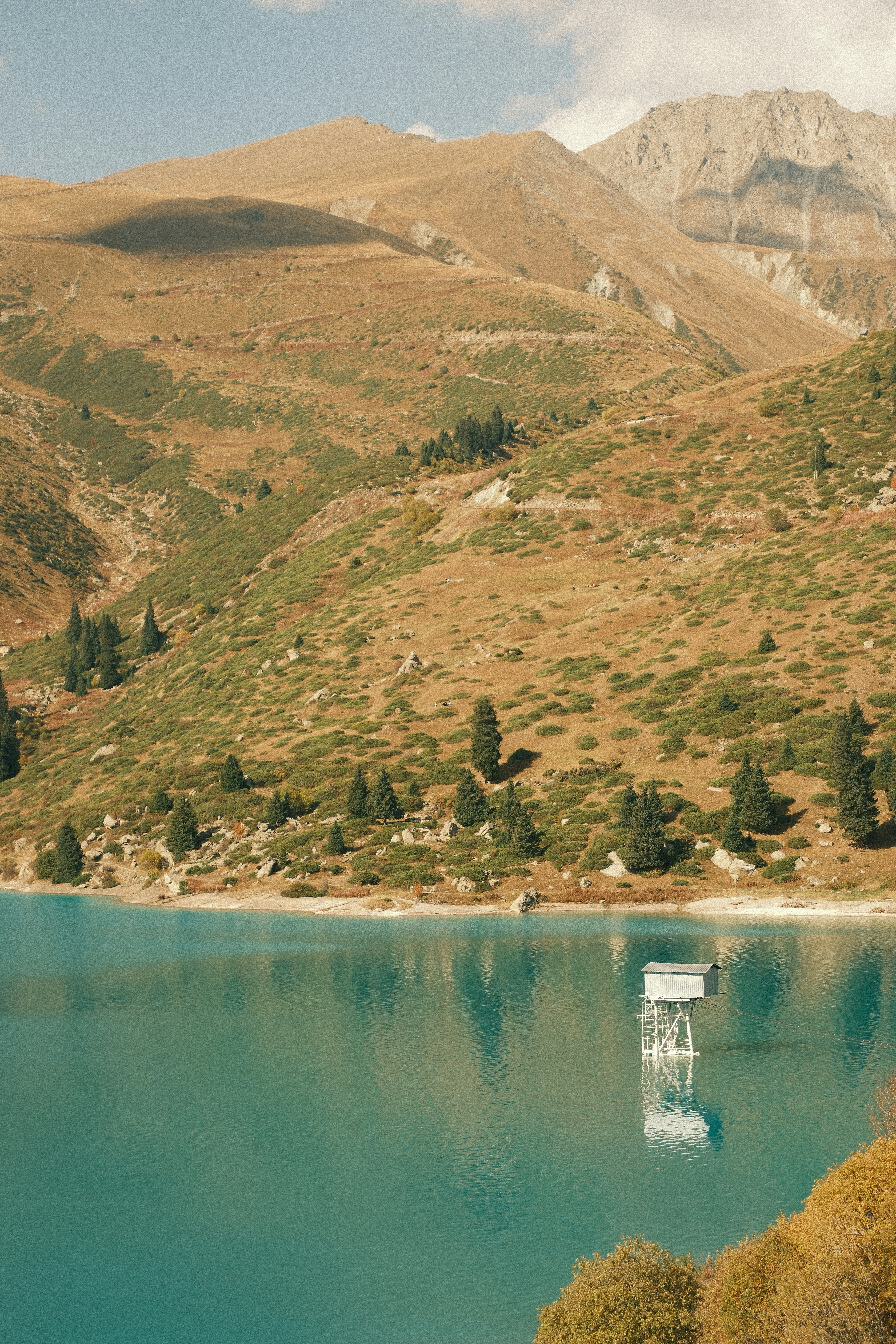 A small metal structure on stilts in a turquoise mountain lake