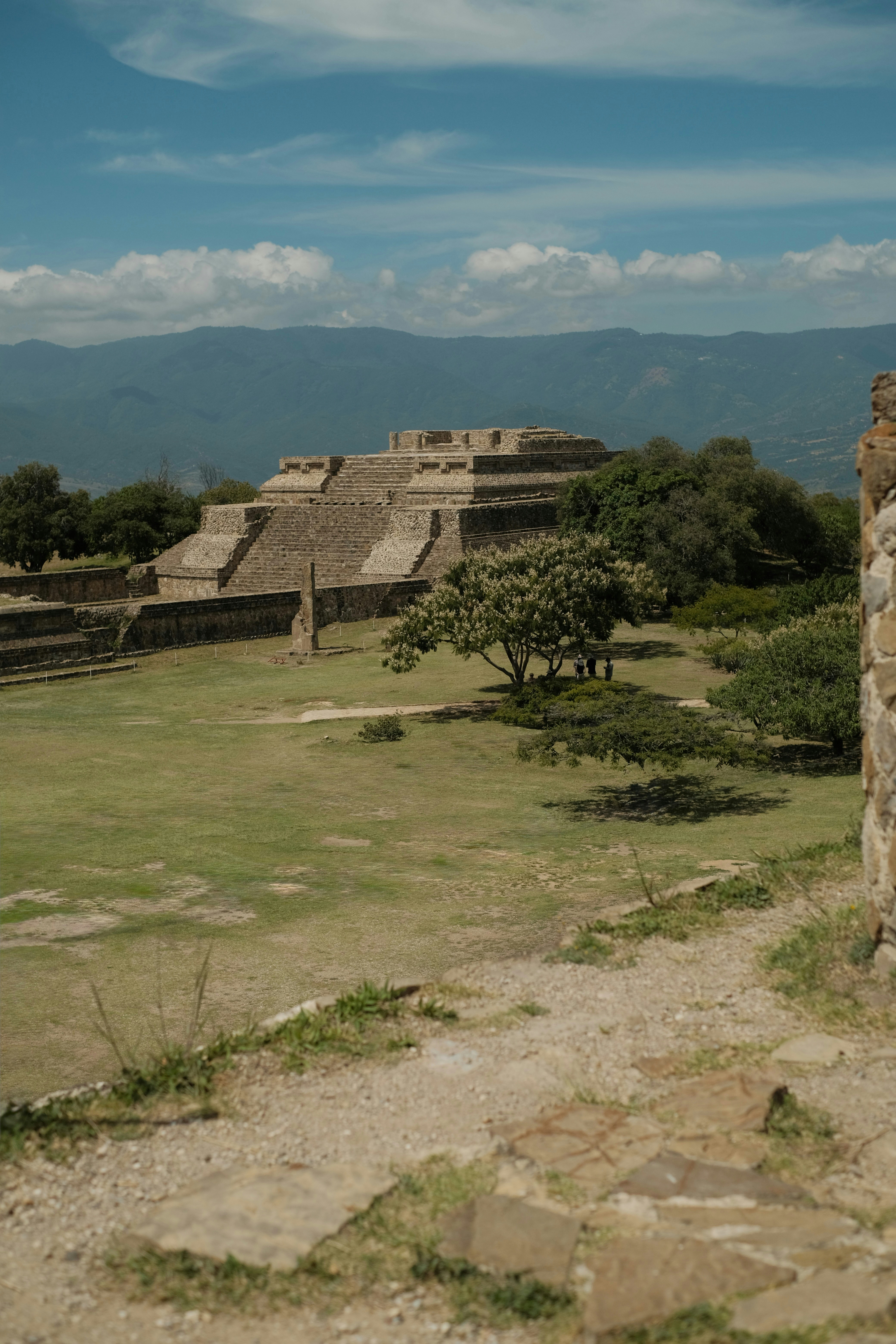 Antiguas ruinas de pirámides de piedra en un campo de hierba con montañas a lo lejos