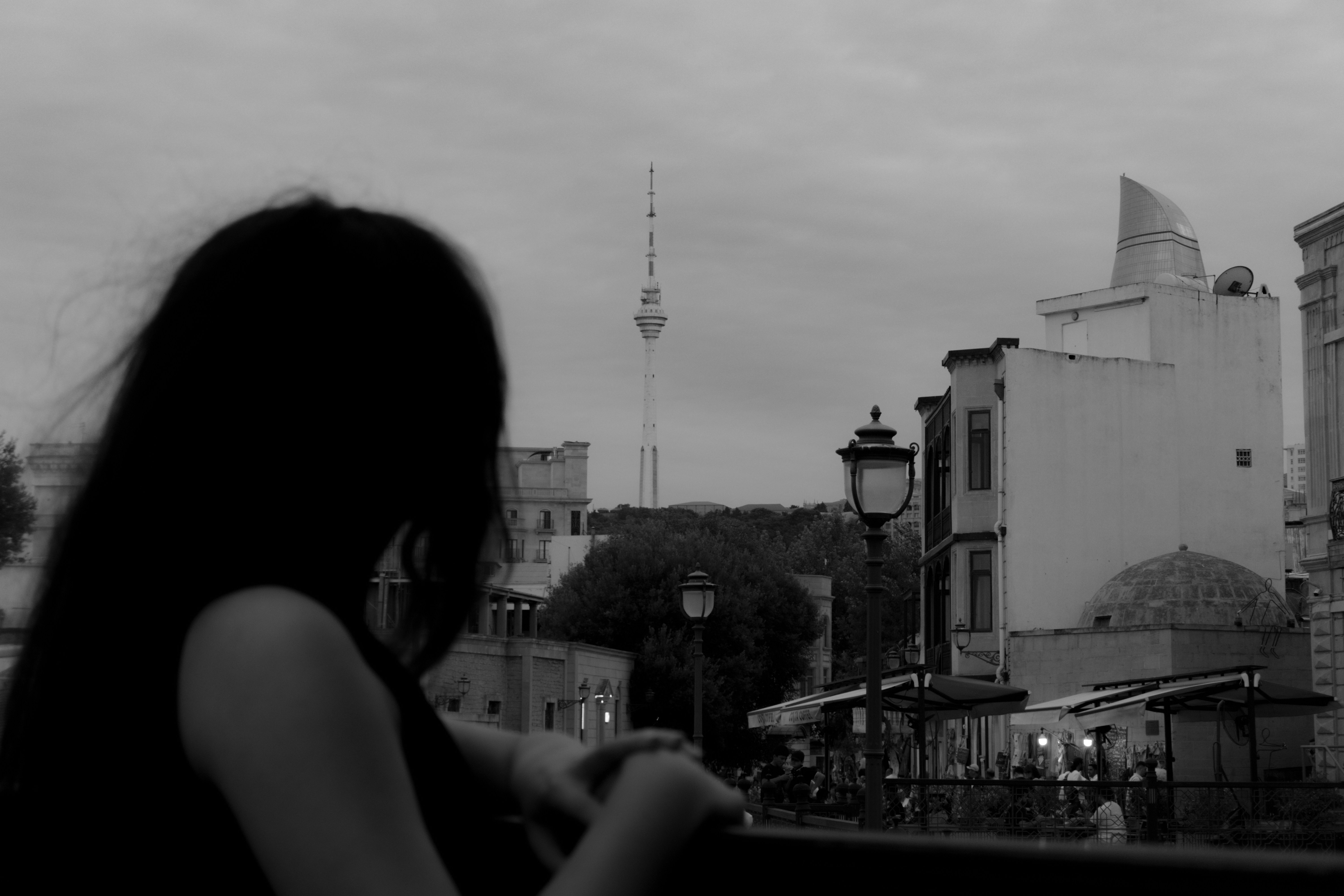 A person in silhouette overlooking a city street with the TV Tower in Baku
