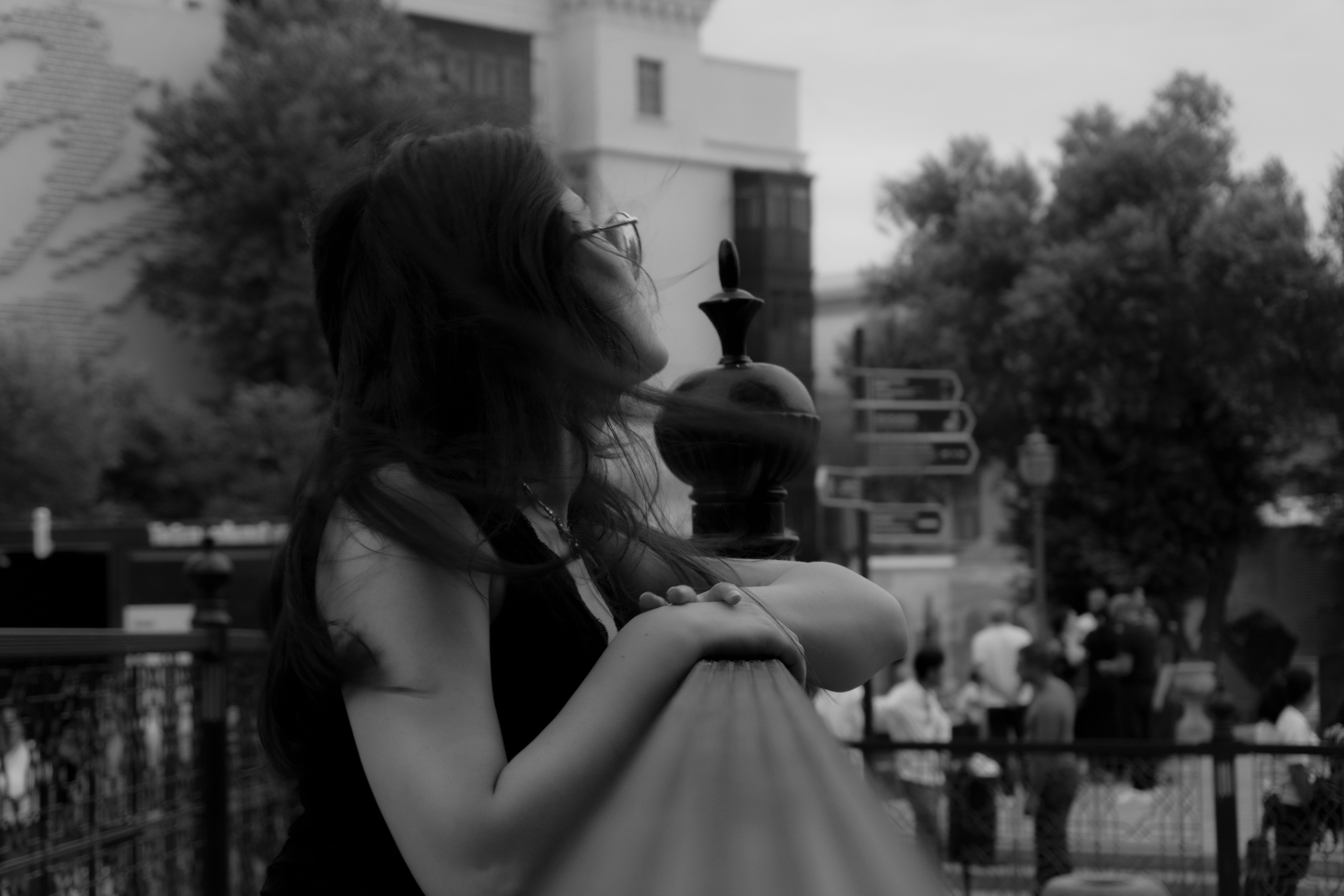 A woman leaning on a metal railing in a public square