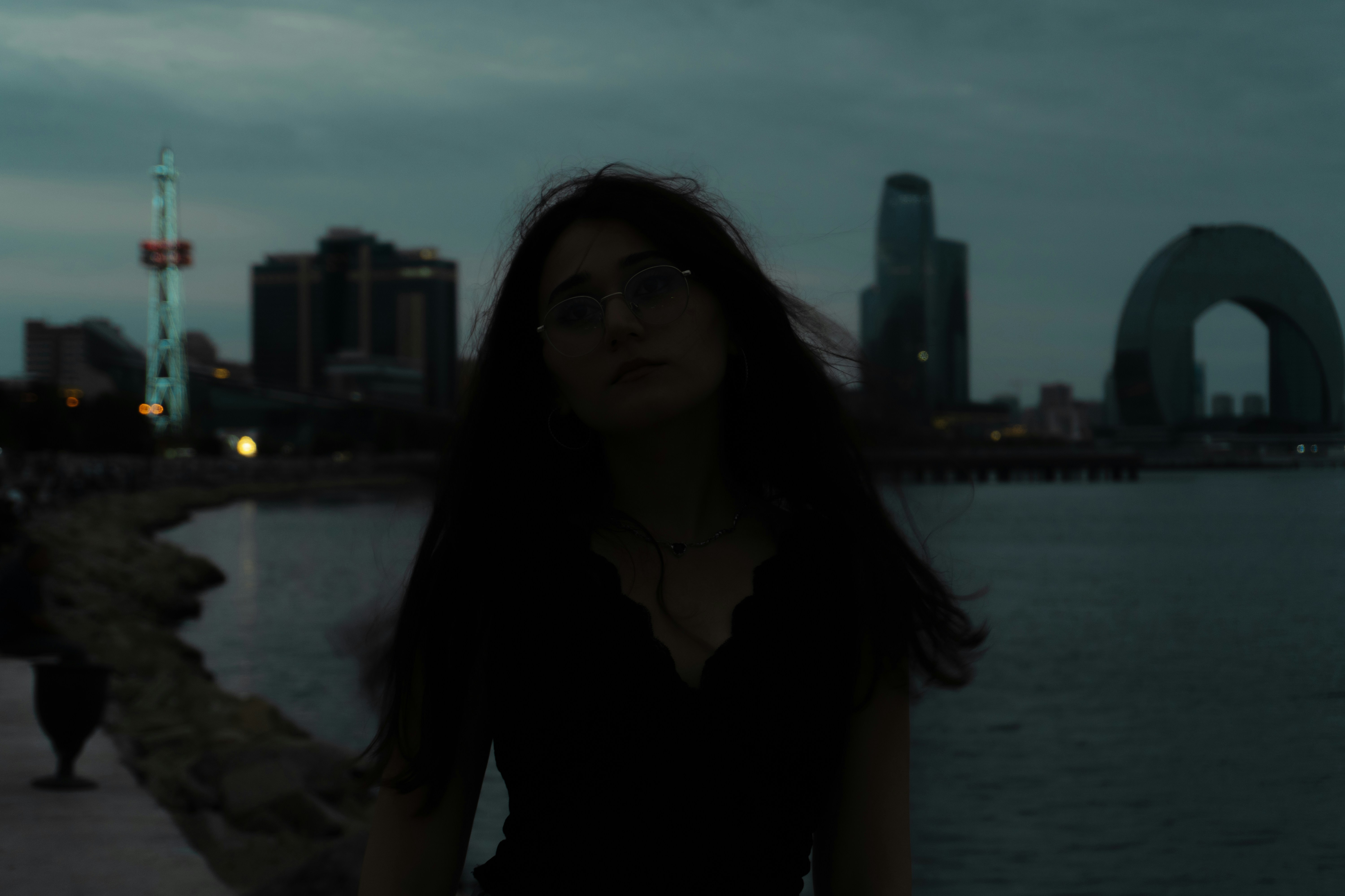 A woman in silhouette against the Baku skyline at dusk