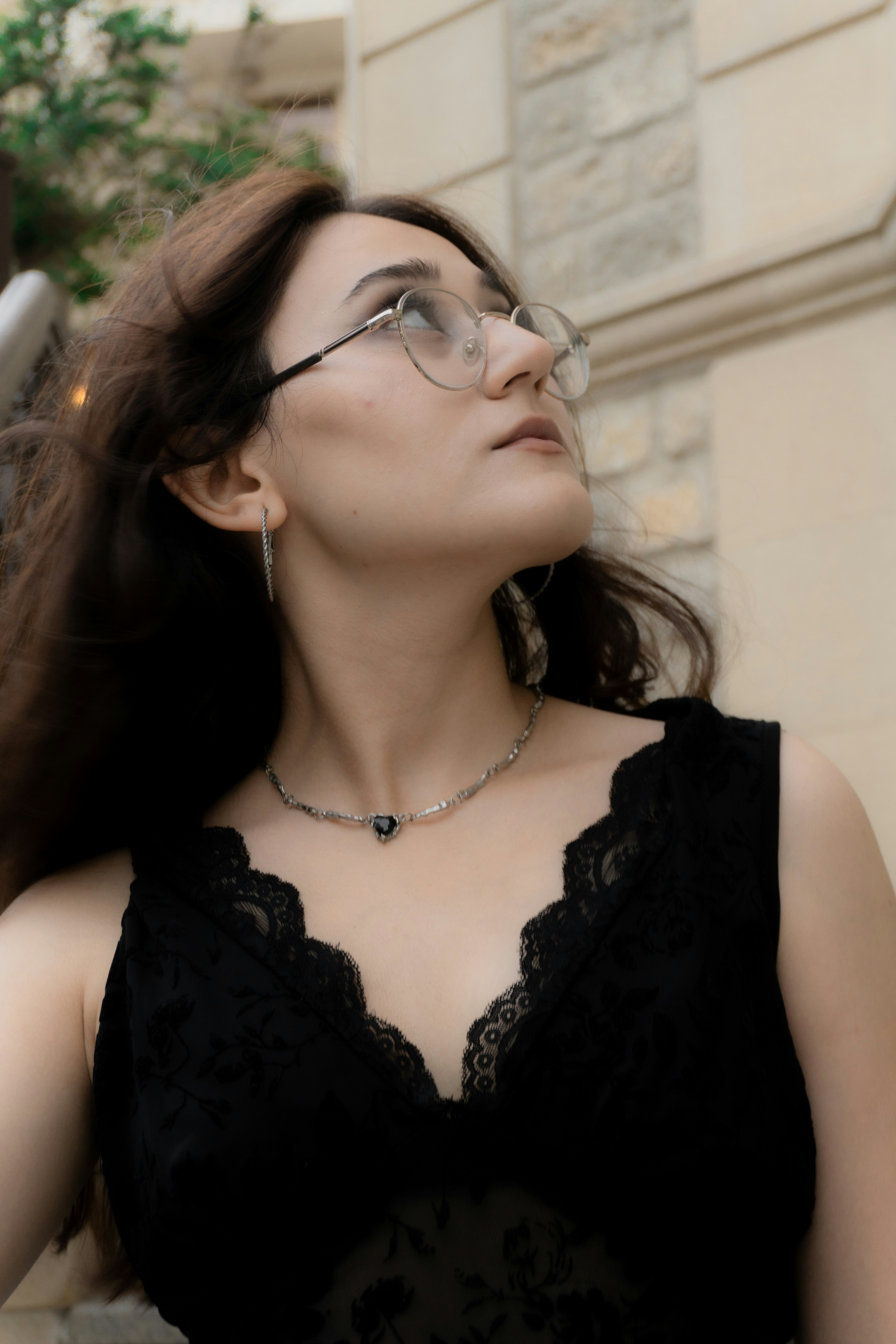 A woman with long brown hair wearing glasses and a black lace top