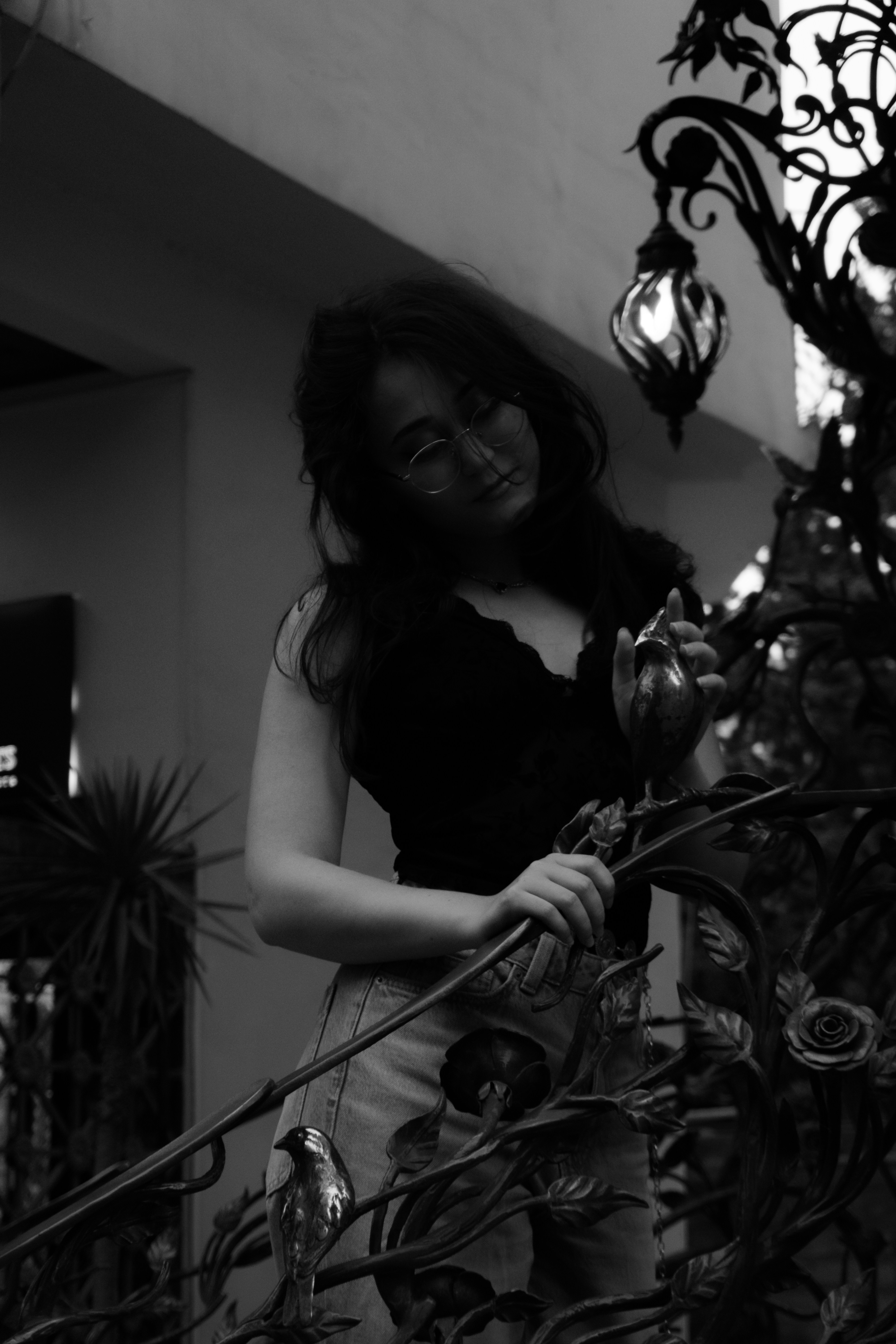 A woman in glasses touching a metal railing with bird and rose ornaments