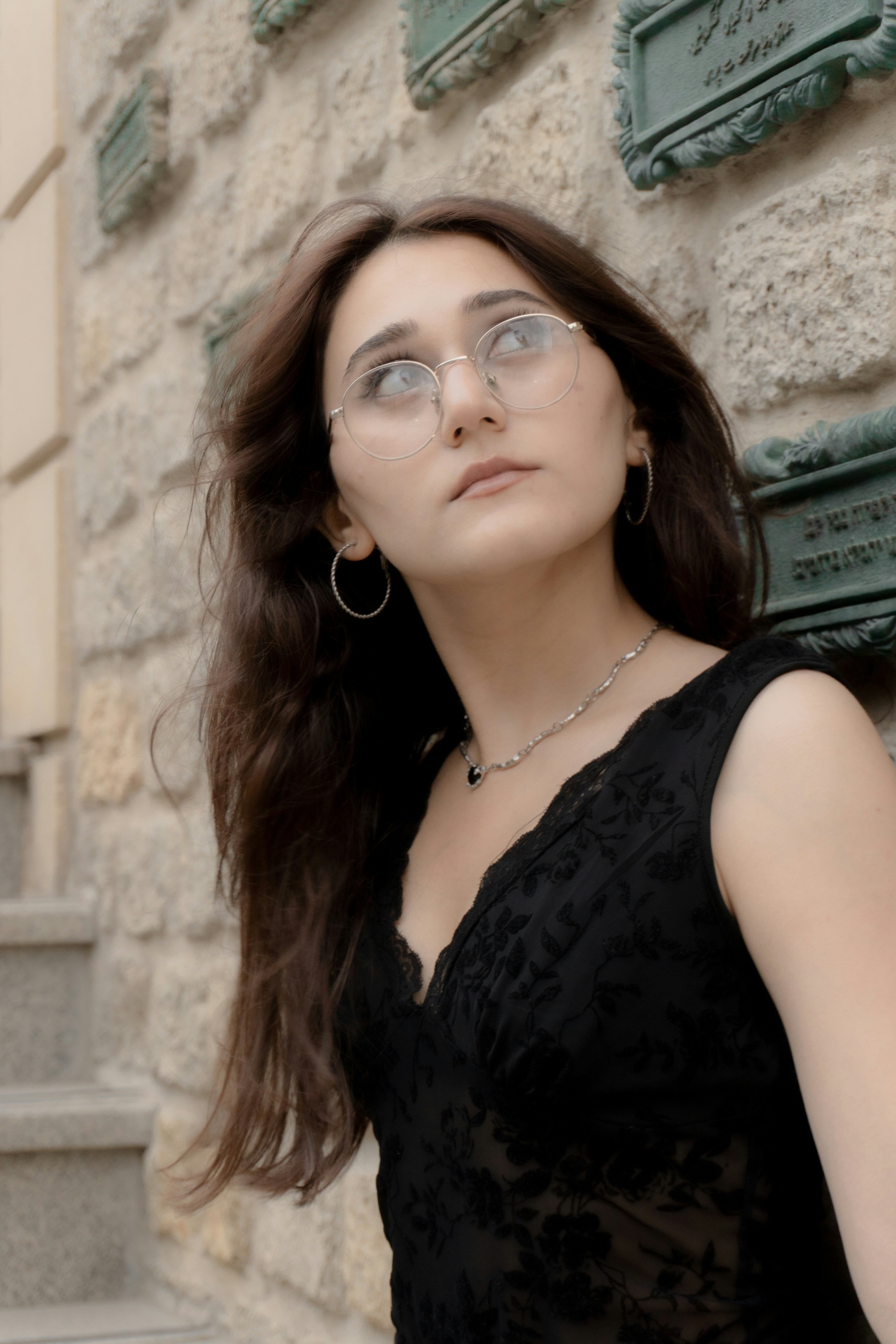 A woman with long dark hair wearing glasses and a black lace top