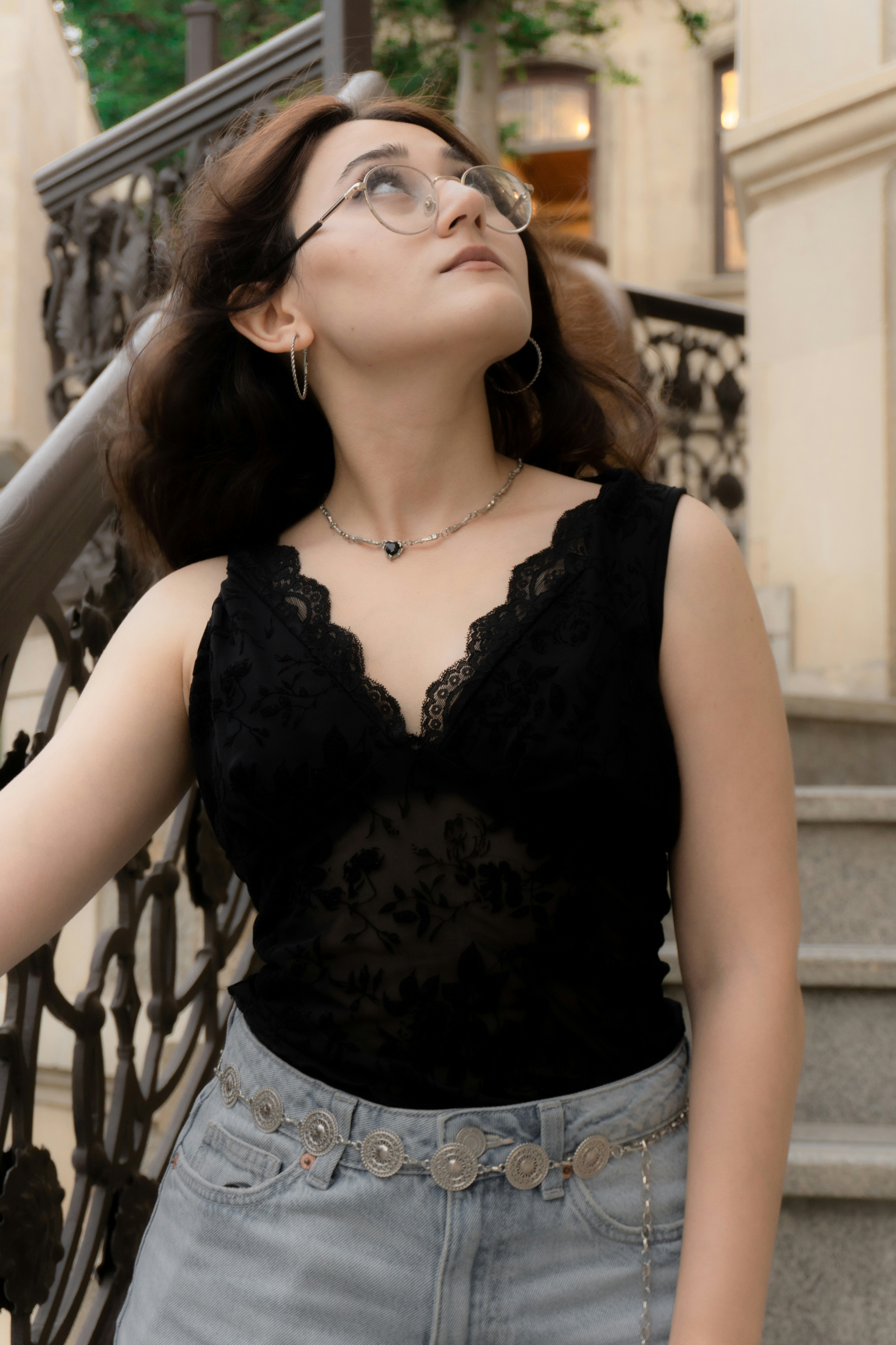 A woman in a black lace top and jeans on a stone staircase