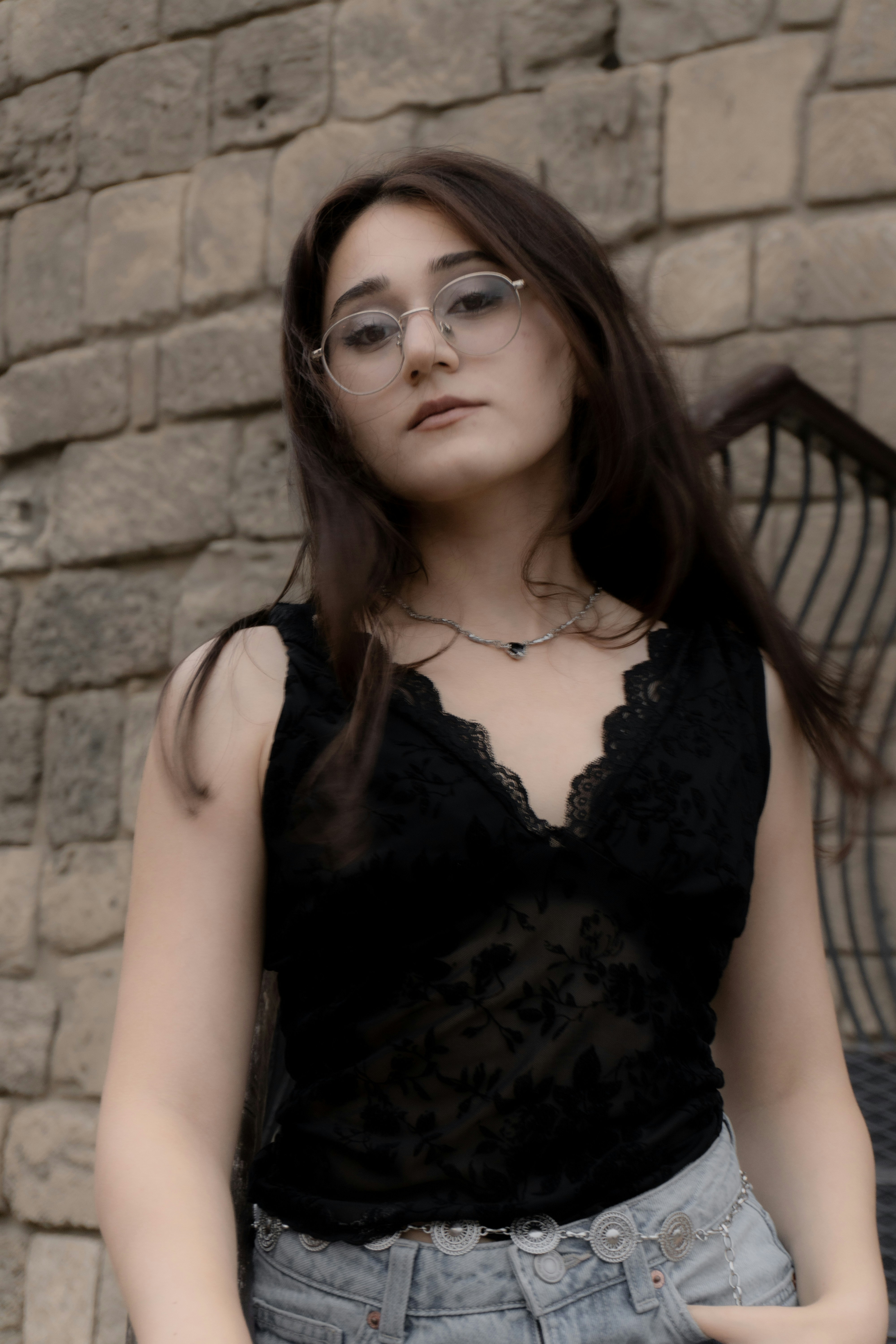 A young woman with long dark hair wearing glasses and a black lace top